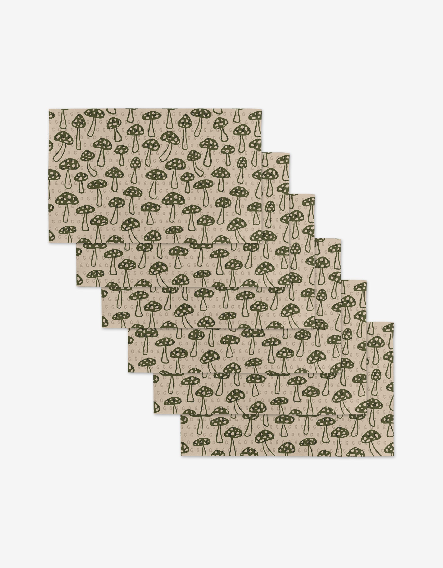 Six Woodland Mushroom placemats by Kayla Ann, made from post-consumer recycled materials, feature a green mushroom pattern on beige. Rectangular and fanned out, they are displayed on a white background.