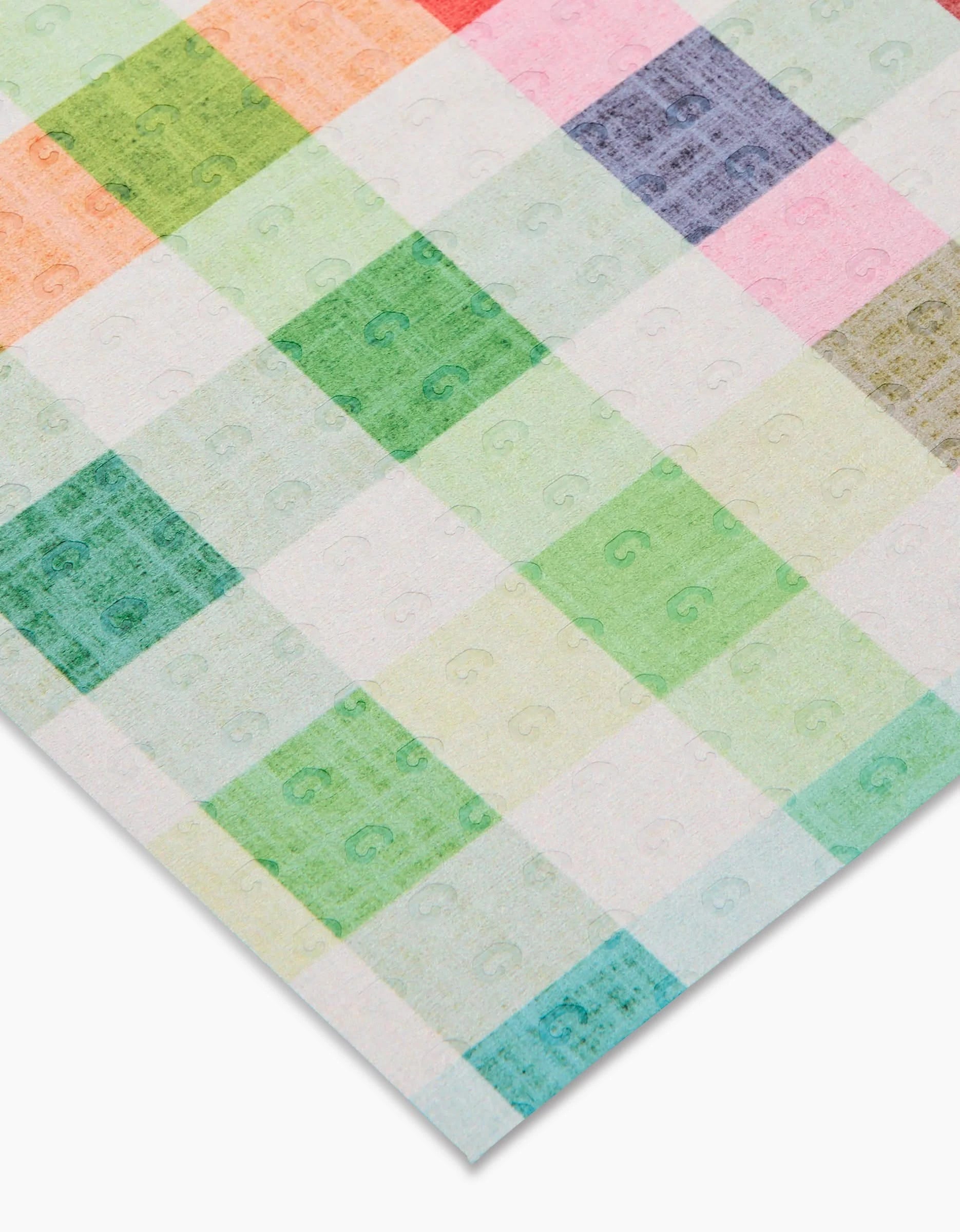 A sheet of Pascale Dilger’s Woven Spring Plaid shows a pastel grid in green, pink, red, and blue squares, each with a faint “G” watermark. Made from post-consumer recycled materials. Not Paper Towel.