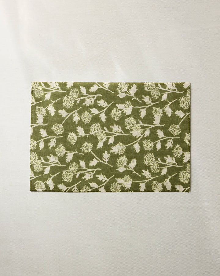 The Geometry Bloom Thistle Green is a rectangular recycled placemat featuring a green background with white botanical leaf and flower designs, shown on an off-white surface.