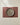 The Geometry Russet eco-friendly placemat in maroon, with a beige ceramic plate on top, rests on a light tablecloth, captured from above for a simple, minimalistic look.