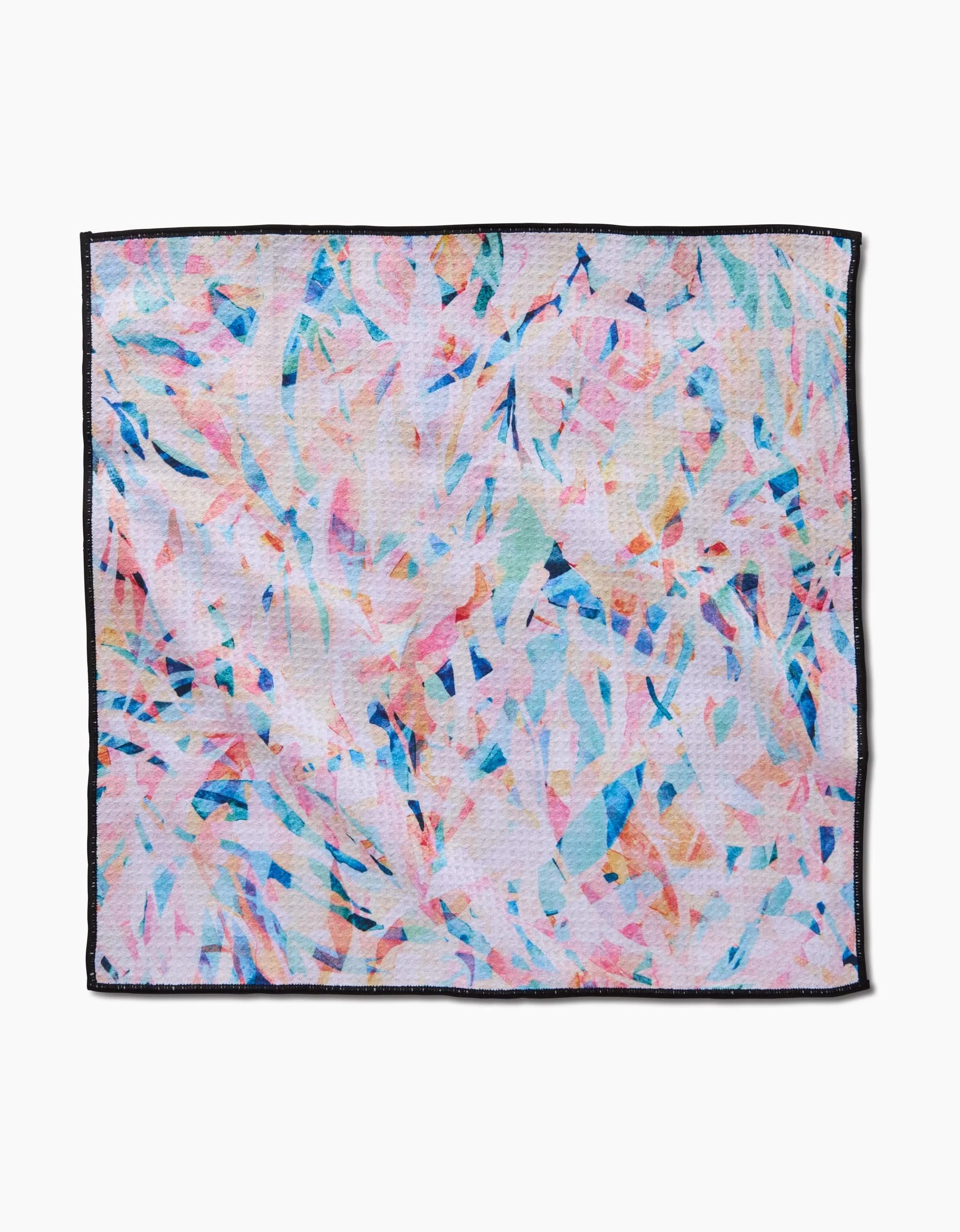 The Rachel Parker Abstract Jungle napkin is a square cloth made from ultra-absorbent Geoweave fabric, featuring a pastel pink, blue, peach, and white abstract pattern with sleek black edging.