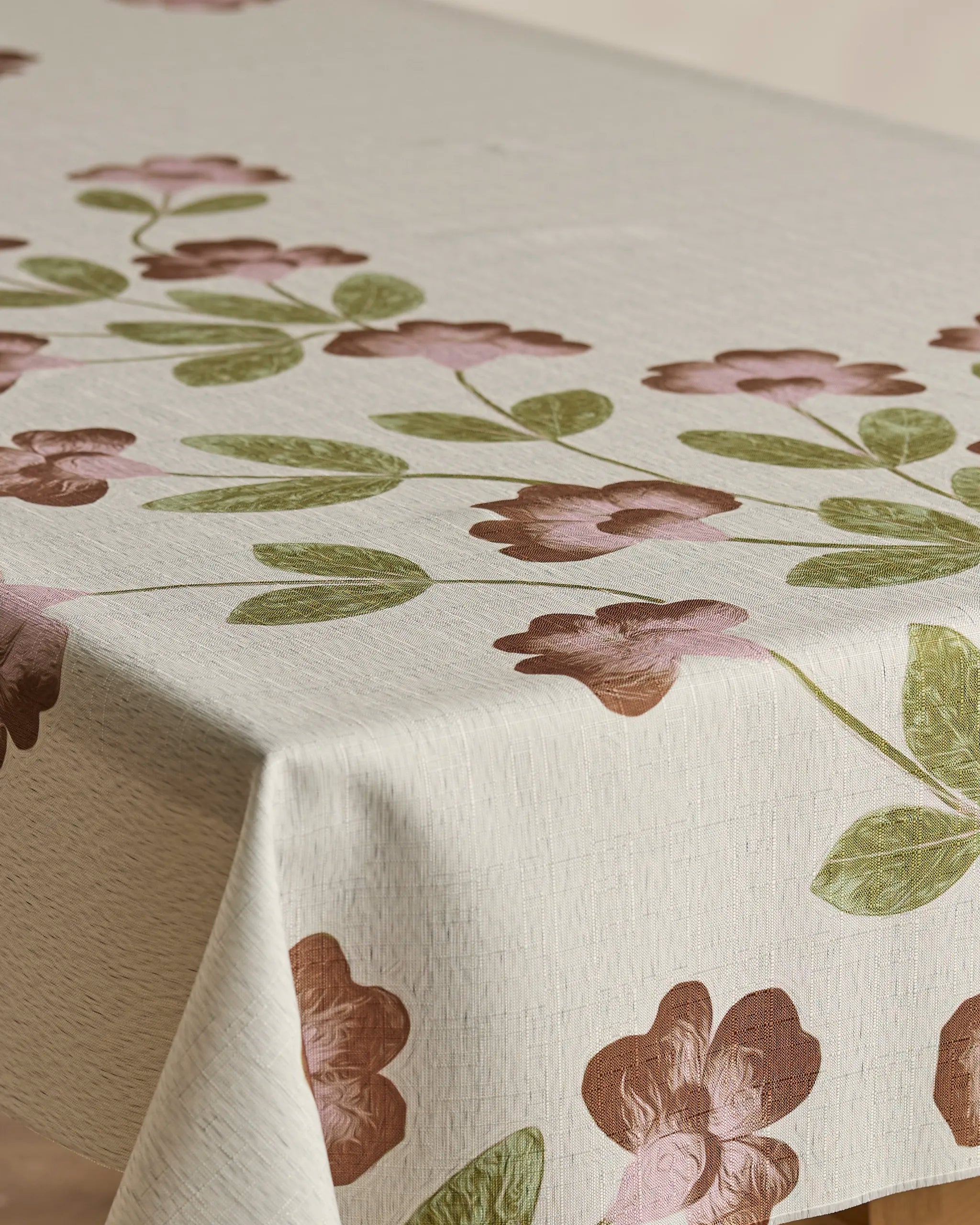The Geometry Flower Tower tablecloth features a spill-resistant beige fabric with pinkish-brown floral patterns and green leaves, elegantly draping over a rectangular table.