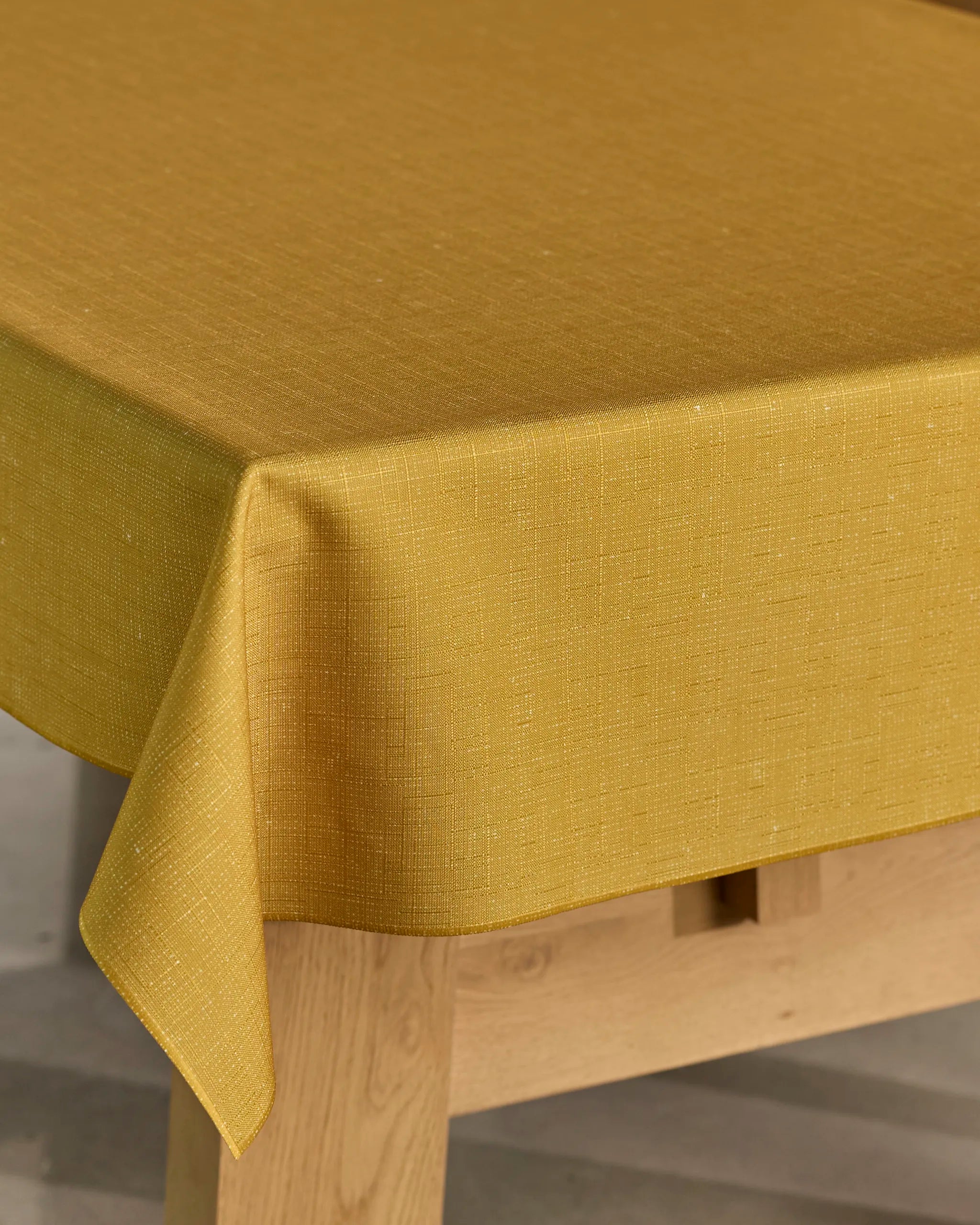 A close-up view of Geometry’s Gather tablecloth in mustard yellow, spill-resistant and rectangular, elegantly draping over the table.