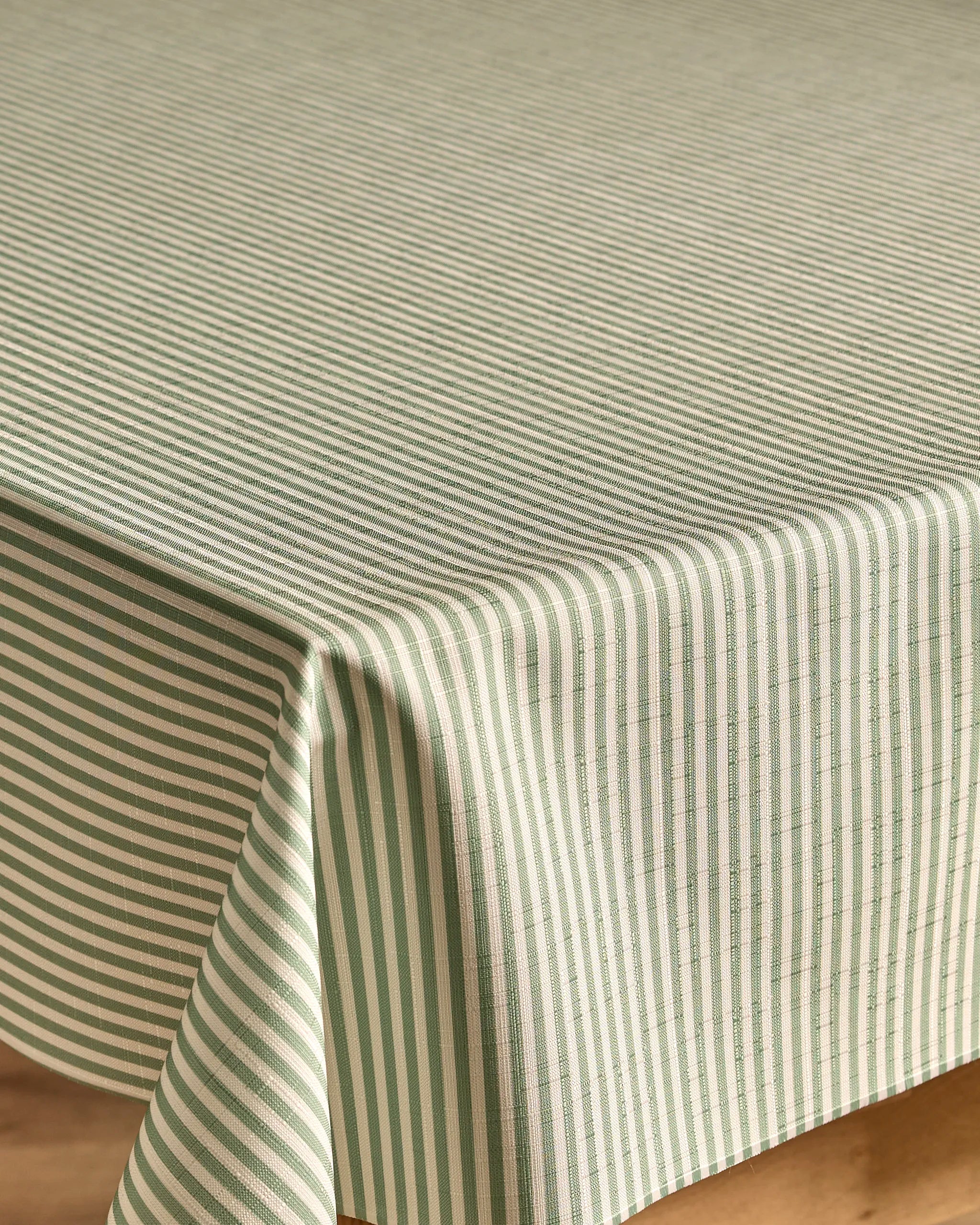 A close-up of a table with the Kailee Wright Mint Green Stripe tablecloth, featuring eco-friendly fabric with green and white stripes—vertical on the sides and horizontal on top for a striking pattern contrast.