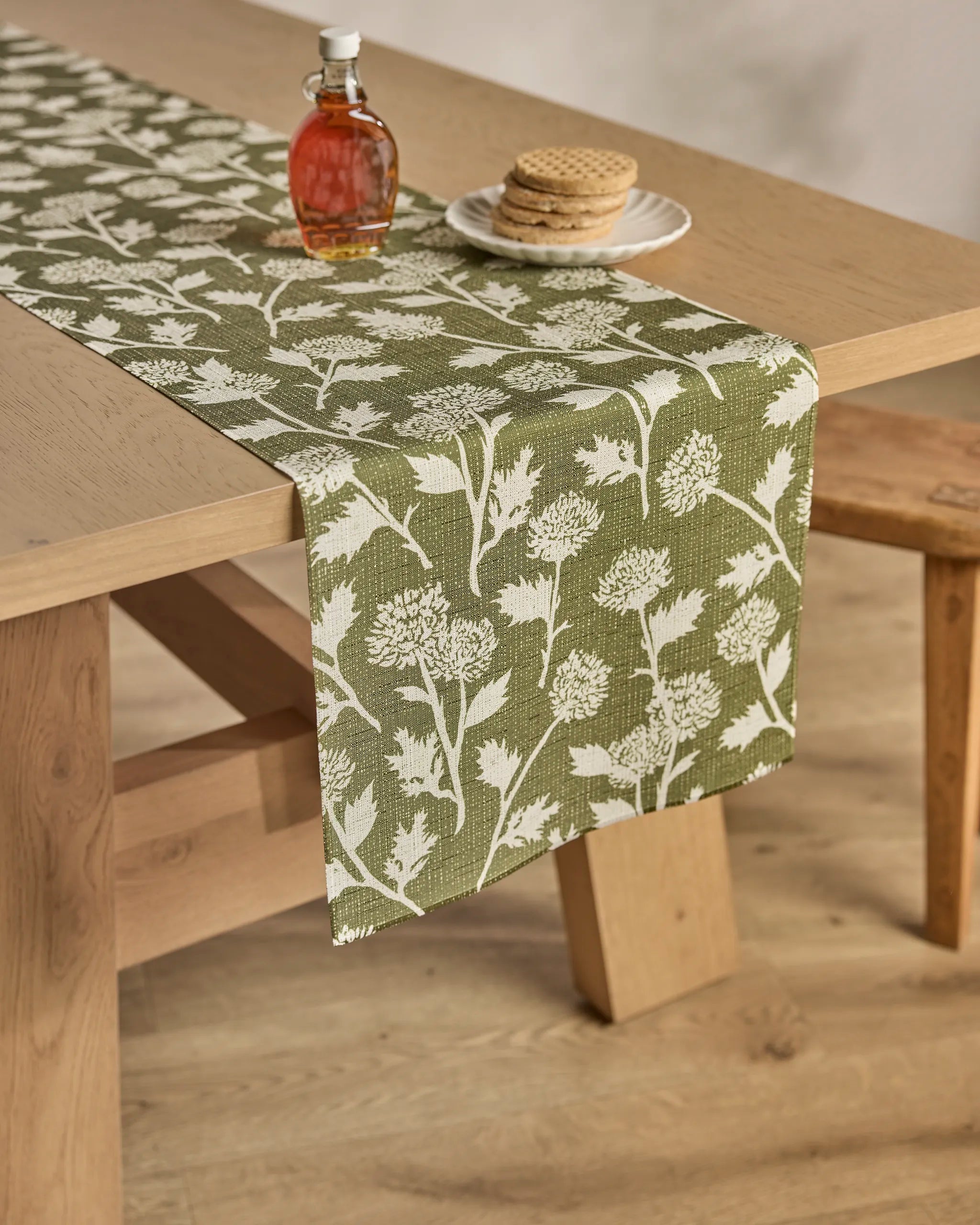 A table featuring the Geometry Bloom Thistle Green stain-resistant table runner, a tablecloth, and cookies.