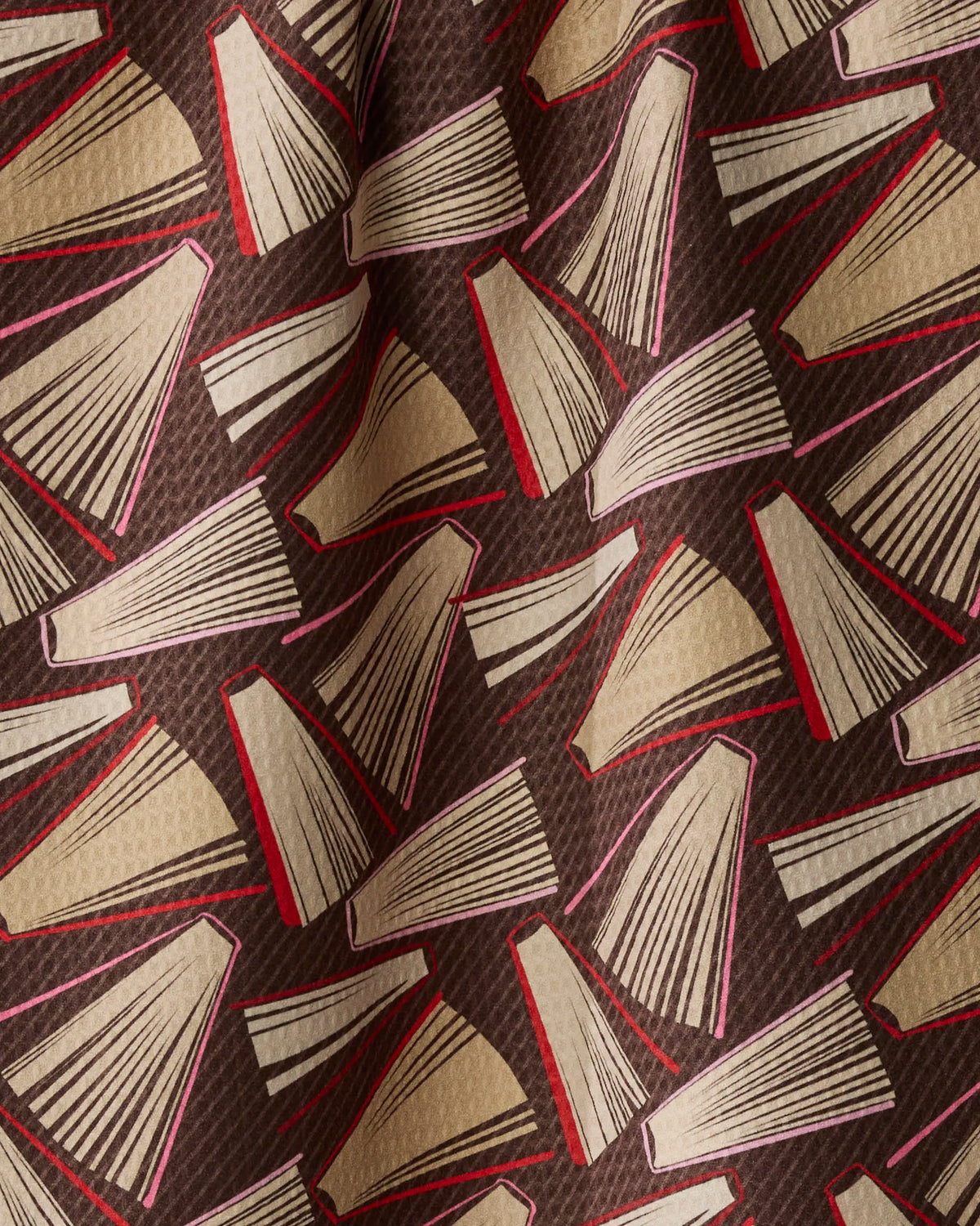 Introducing “Bookmas” by Geometry—a double-sided tea towel featuring patterned fabric adorned with illustrations of open books in beige, brown, and red hues. Arranged in various directions against a textured dark background with striking red accents on some pages and covers, this quick-drying kitchen accessory blends everyday practicality with literary-inspired design.