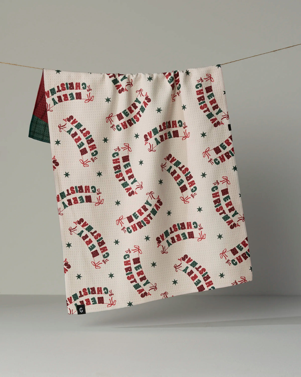 Brighten up your holiday kitchen with the Geometry Christmas Crafts Tea Towel—a festive, double-sided towel crafted from recycled materials. Adorned with cheerful candy canes, green stars, and “Christmas” spelled out in red and green letters on a crisp white background, this eco-friendly tea towel is not only quick-drying but also the perfect way to add holiday spirit to your home.