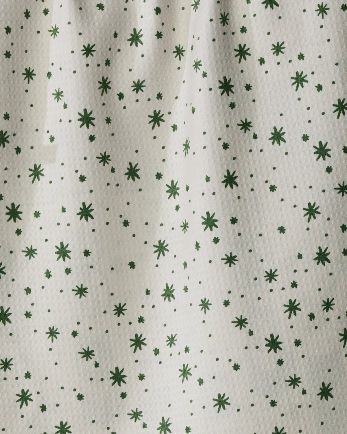 Cozy Kittens by Geometry features a white textured fabric adorned with small, randomly scattered green stars and dots. Subtle folds and shadows on the surface enhance the simple design with extra depth. This quick-drying tea towel brings both charm and practical performance to your kitchen for everyday use.
