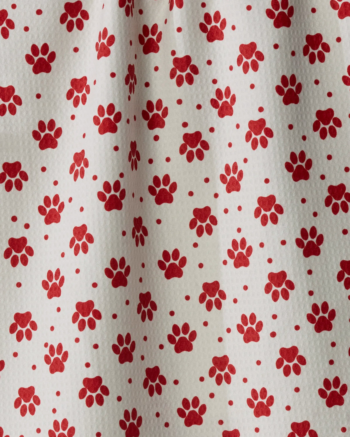 Sure! Here is the revised sentence using the provided product and brand information: Dachshund Dash by Geometry features white GeoLUXE Fabric adorned with a repeating pattern of red animal paw prints and small red dots. Reminiscent of a LUXE Kitchen Tea Towel, this premium fabric appears slightly wrinkled in places, enhancing its cozy and authentic charm.
