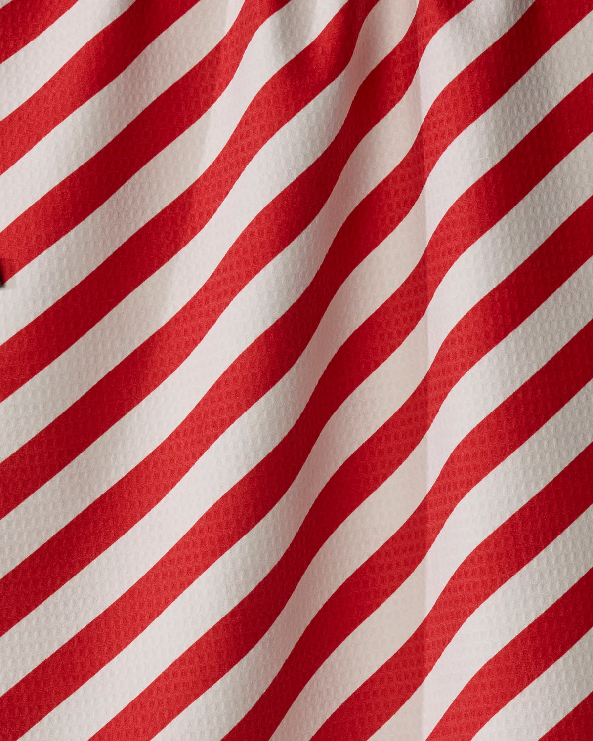 Peppermint Lane by Geometry features red and white diagonal stripes on textured, quick-drying fabric. Gentle folds create a wavy pattern and subtle shadows, making this tea towel both stylish and practical for everyday use.