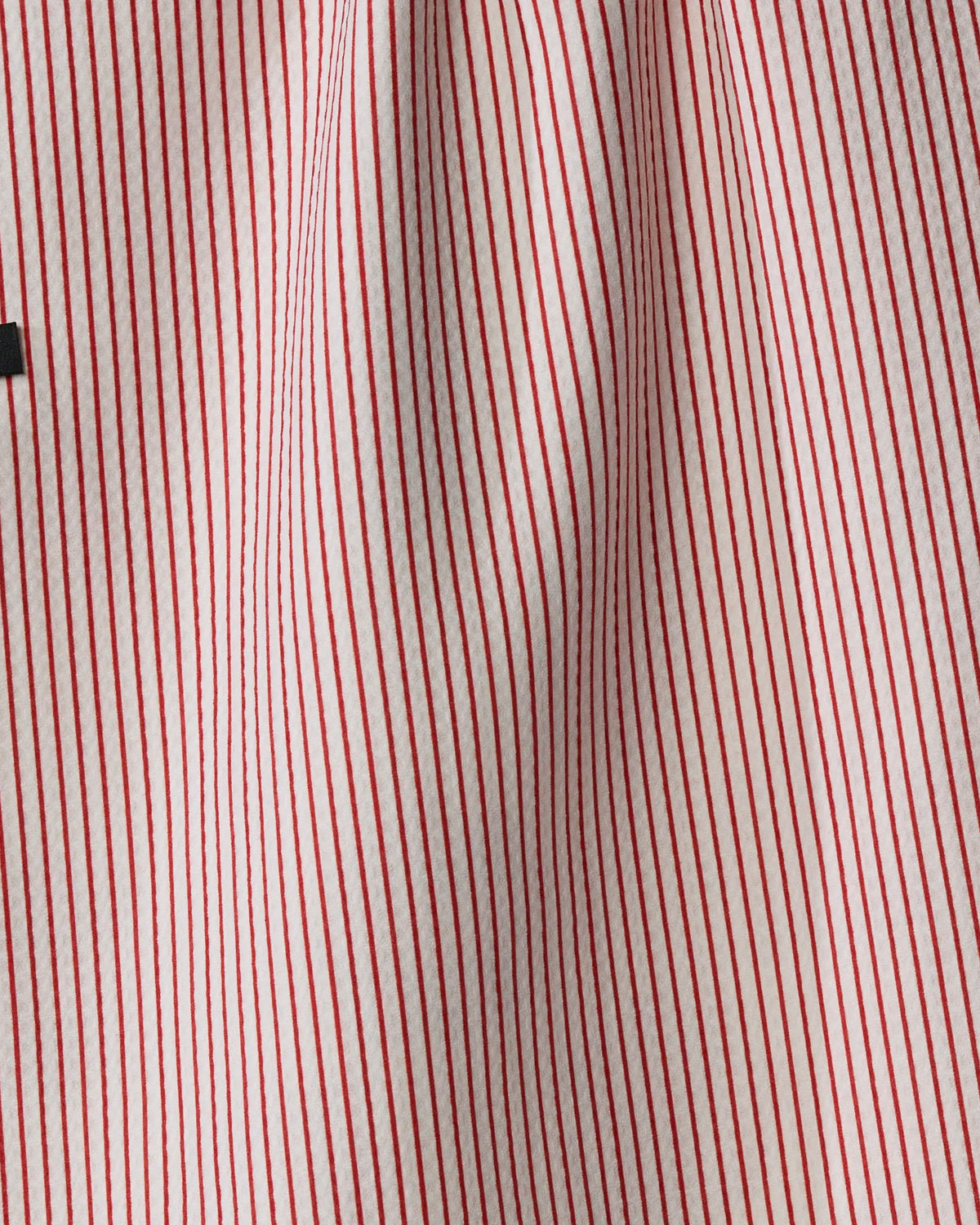 Close-up of Geometry’s Perfectly Wrapped recycled kitchen towel, showcasing red and white vertical stripes and a central fold that creates a wavy, textured look.