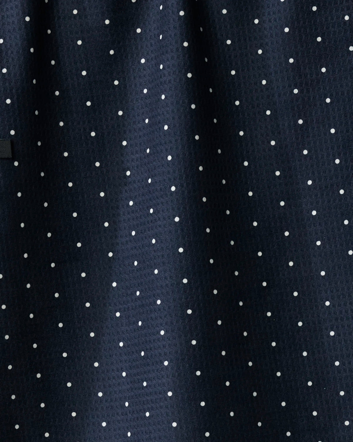 Introducing Quiet Skies by Geometry—a dark navy blue towel adorned with evenly spaced small white polka dots for a classic dotted pattern. This absorbent, quick-dry kitchen essential combines stylish design with everyday practicality.