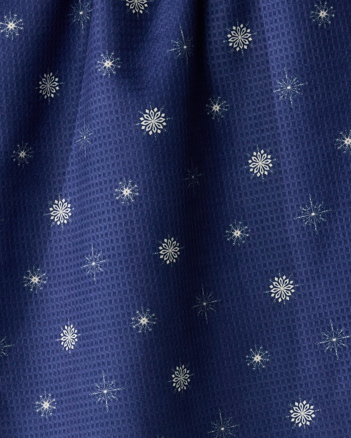 Snowflake Chalet by Geometry is a double-sided tea towel featuring dark blue textured fabric adorned with small white snowflakes, offering both style and practicality—ideal for adding winter charm to your kitchen.