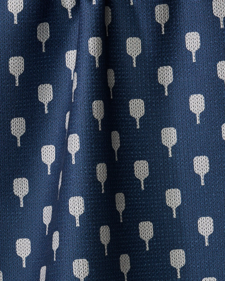 Close-up of The Modern Dad's Mr. Pickler tea towel in blue, featuring a repeating pattern of small white tree-like shapes. Made from recycled materials, the fabric has subtle folds and a textured surface.