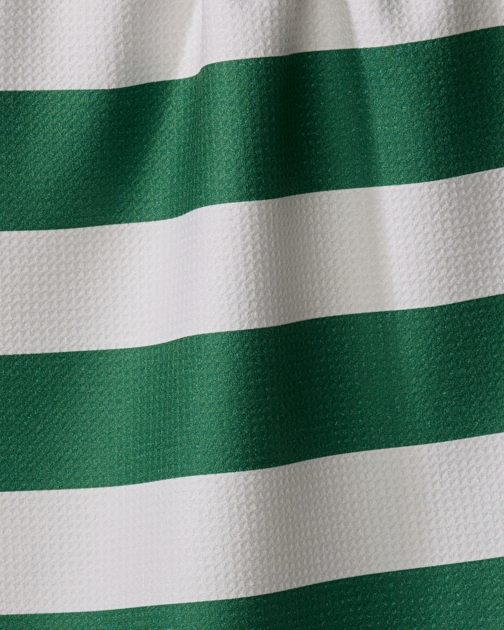 Close-up of The Modern Dad’s Mr. Day On The Green kitchen towel, made from recycled materials with textured horizontal green and white stripes and soft folds.