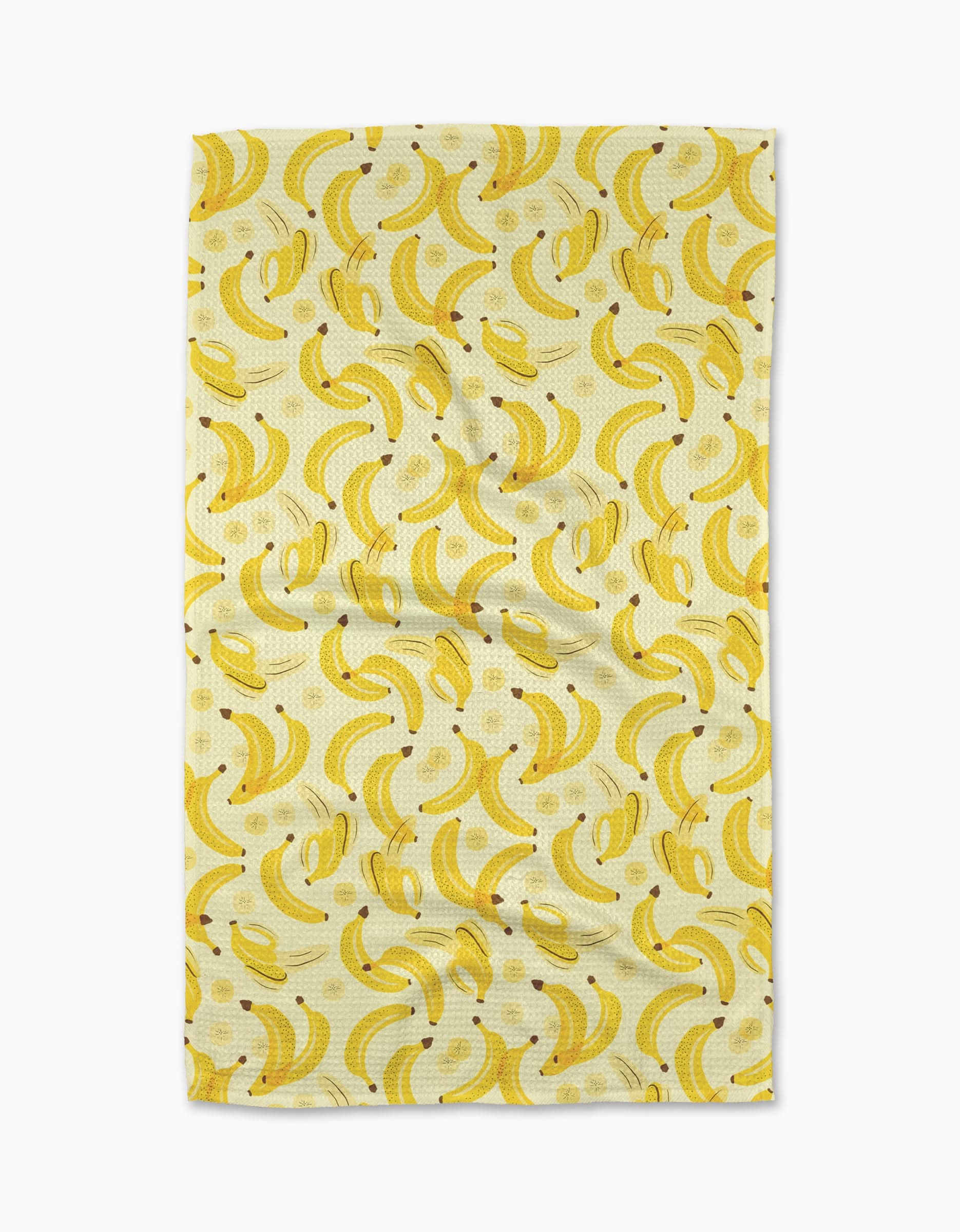 The A Bunch of Bananas Tea Towel by Geometry features a repeating yellow banana pattern on a light Geoweave fabric, shown slightly wrinkled against a plain white background.