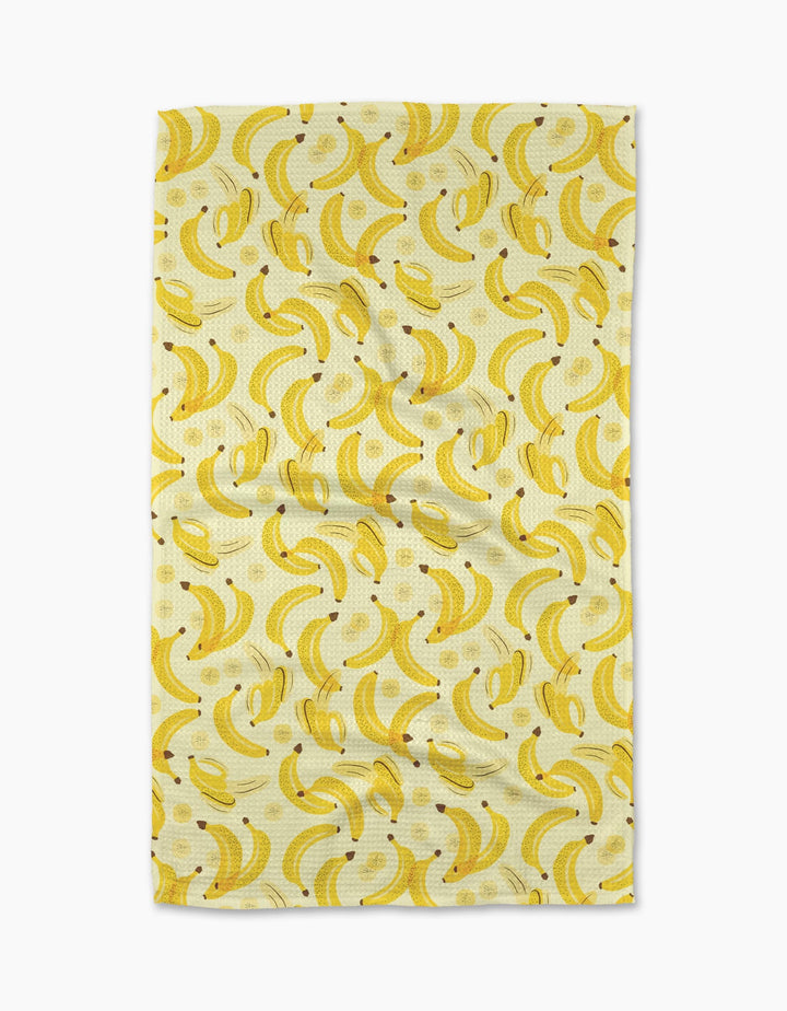 The A Bunch of Bananas Tea Towel by Geometry features a repeating yellow banana pattern on a light Geoweave fabric, shown slightly wrinkled against a plain white background.