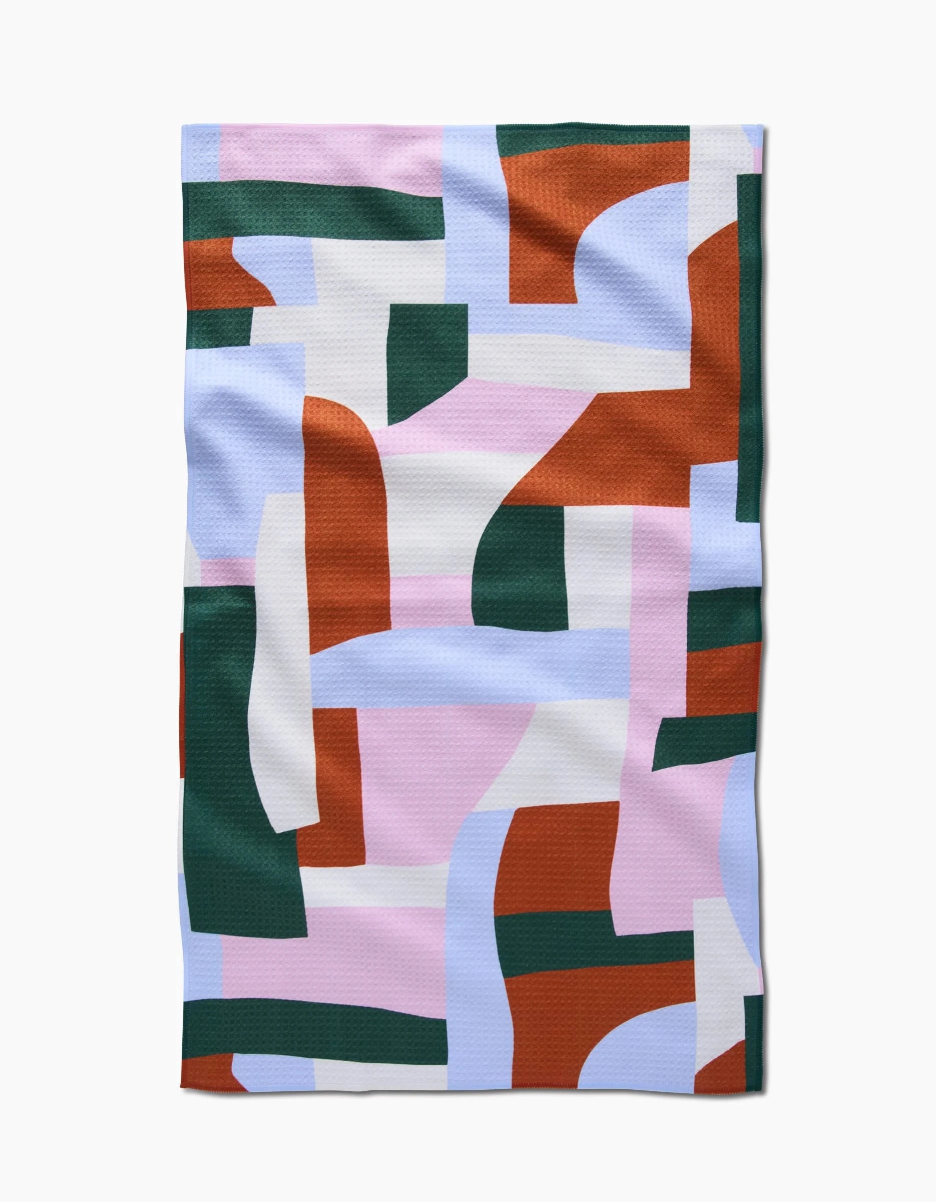 The Abstract Collage tea towel by Claire Iglesias features an abstract geometric pattern in rust orange, forest green, pale pink, white, and light blue. Made from recycled materials with slight wrinkles, it’s displayed on a white background.