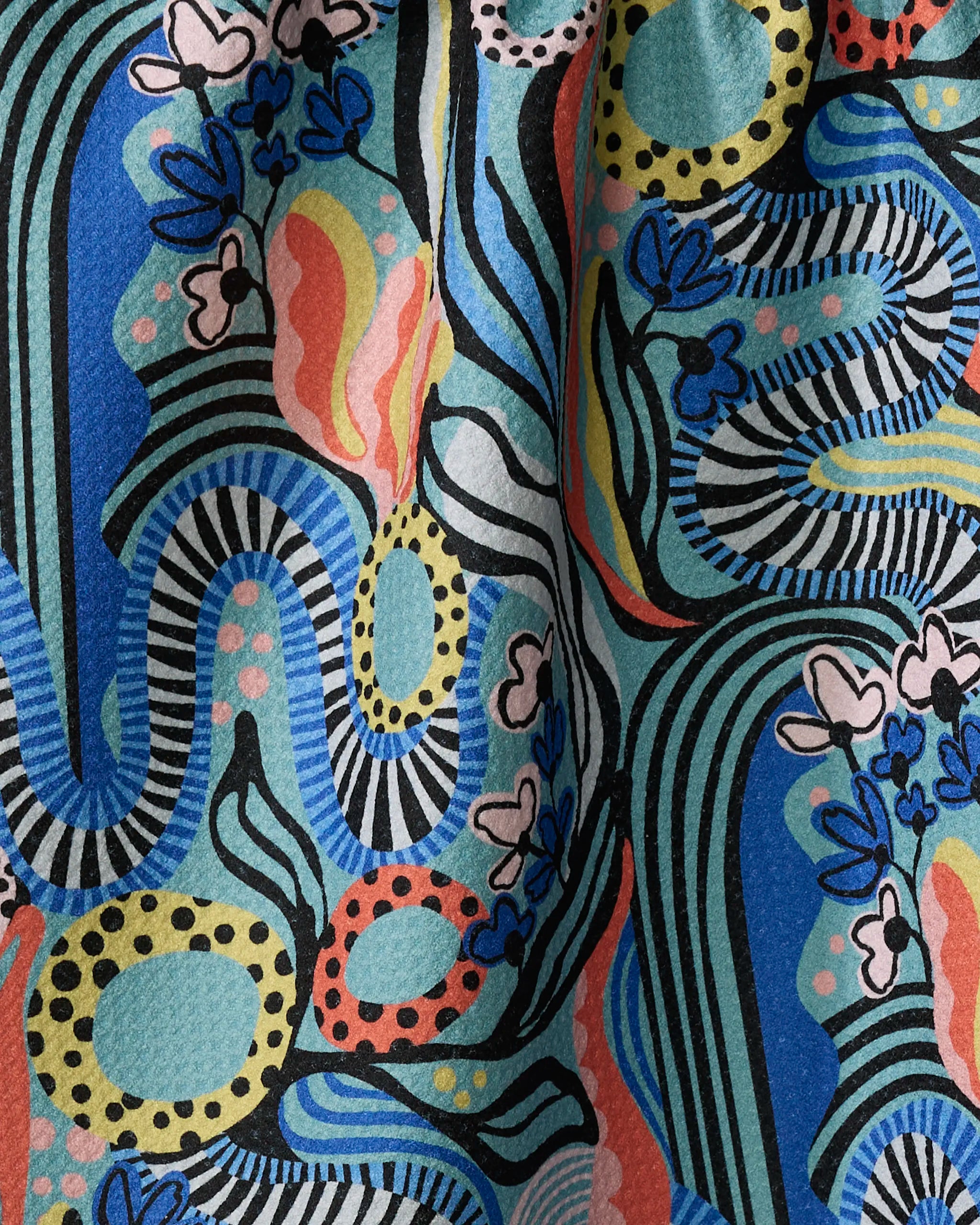 The "Abstract Dreams" kitchen towel by Masha Volnova features wavy black and white stripes, blue and red curves, yellow dotted circles, and stylized flowers and leaves on a vibrant blue background.