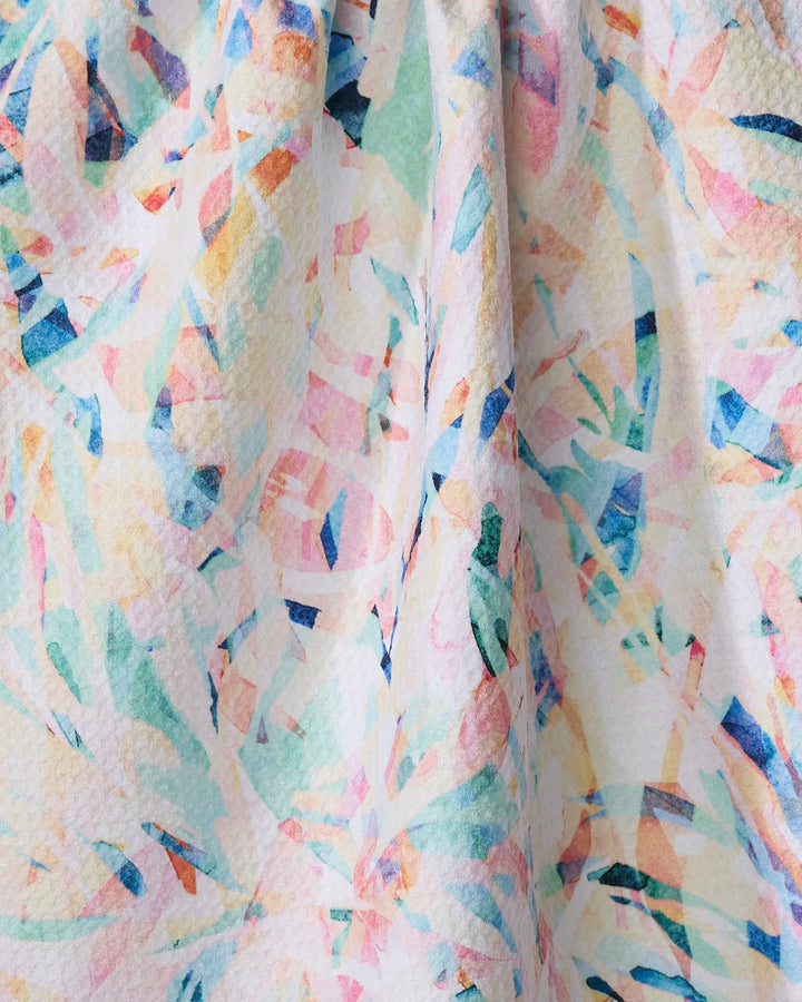 A close-up of Rachel Parker’s Abstract Jungle tea towel shows its textured fabric with an abstract, colorful pattern in pastel pink, blue, green, and orange with overlapping shapes and brushstrokes.