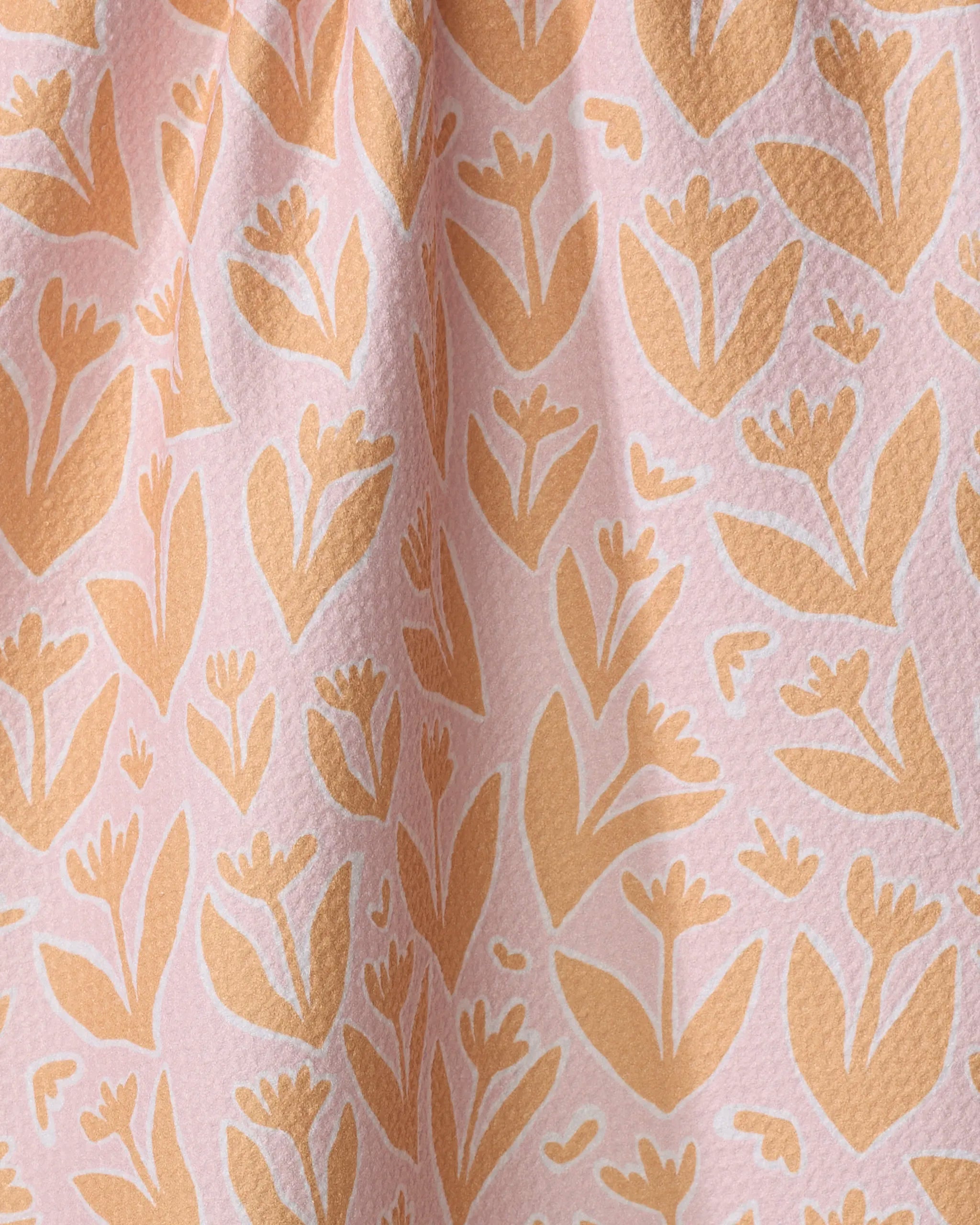 Close-up of Kayla Ann’s "Abstract Tulips" fabric, featuring textured material and a repeating pattern of stylized orange tulips and leaves on a light pink background—ideal for a charming, absorbent dish towel.