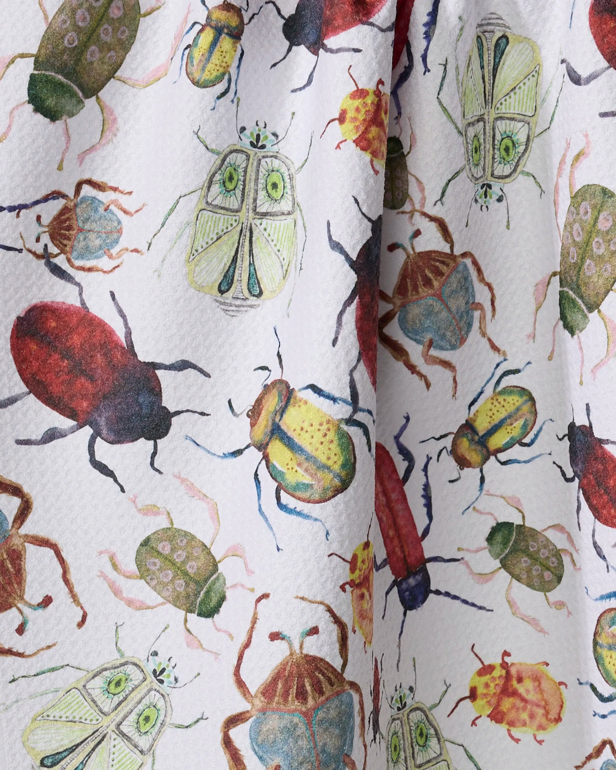 A close-up of the Taryn Brennan "African Beetles" tea towel, showcasing a colorful, detailed pattern of illustrated beetles and insects on a white background.