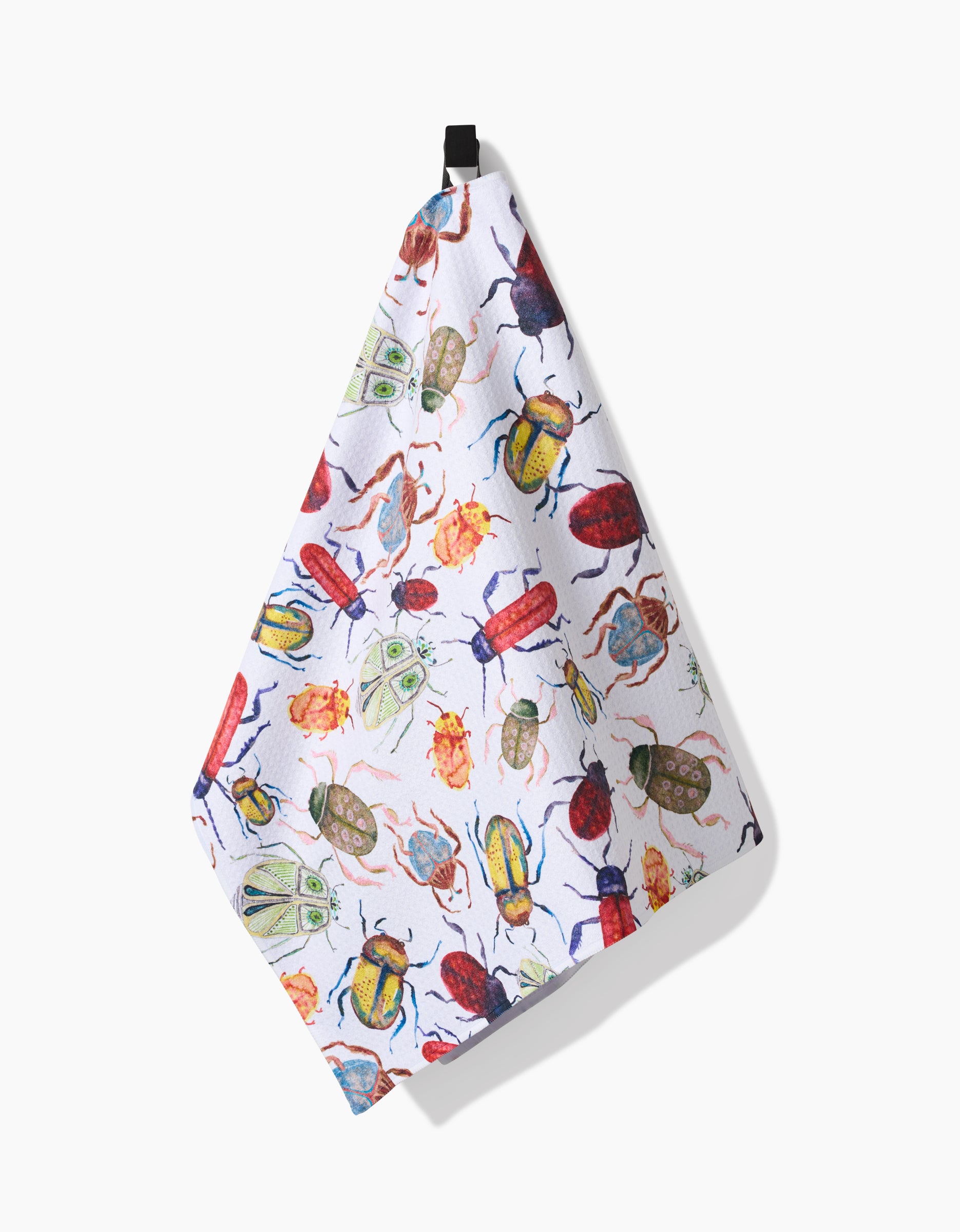 The African Beetles tea towel by Taryn Brennan hangs from a black loop, showcasing a vibrant pattern of illustrated beetles and moths on white, crafted from recycled materials.