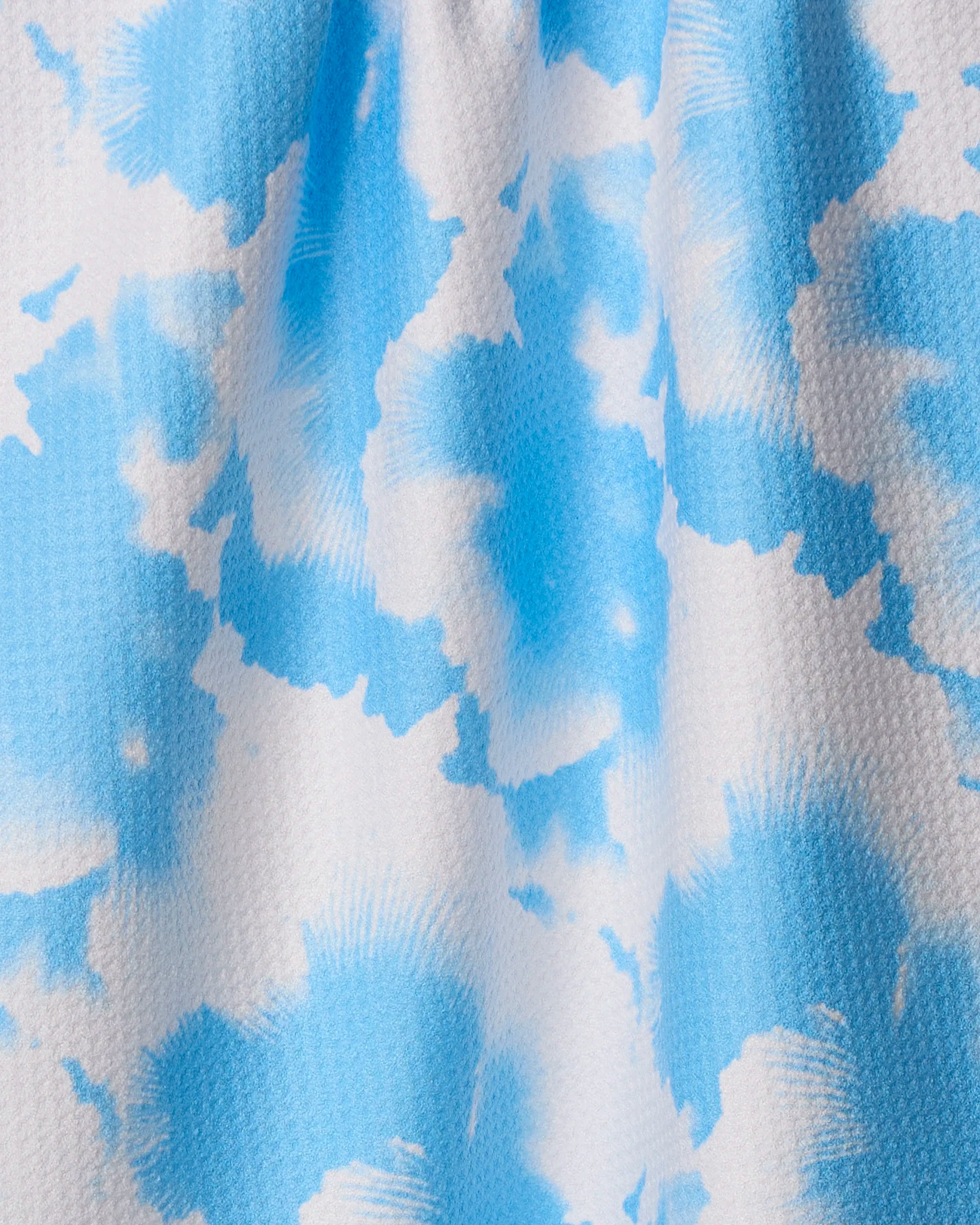Close-up of the Geometry Alicia quick-drying towel, showcasing its blue and white tie-dye pattern with soft, cloud-like shapes and a textured surface.