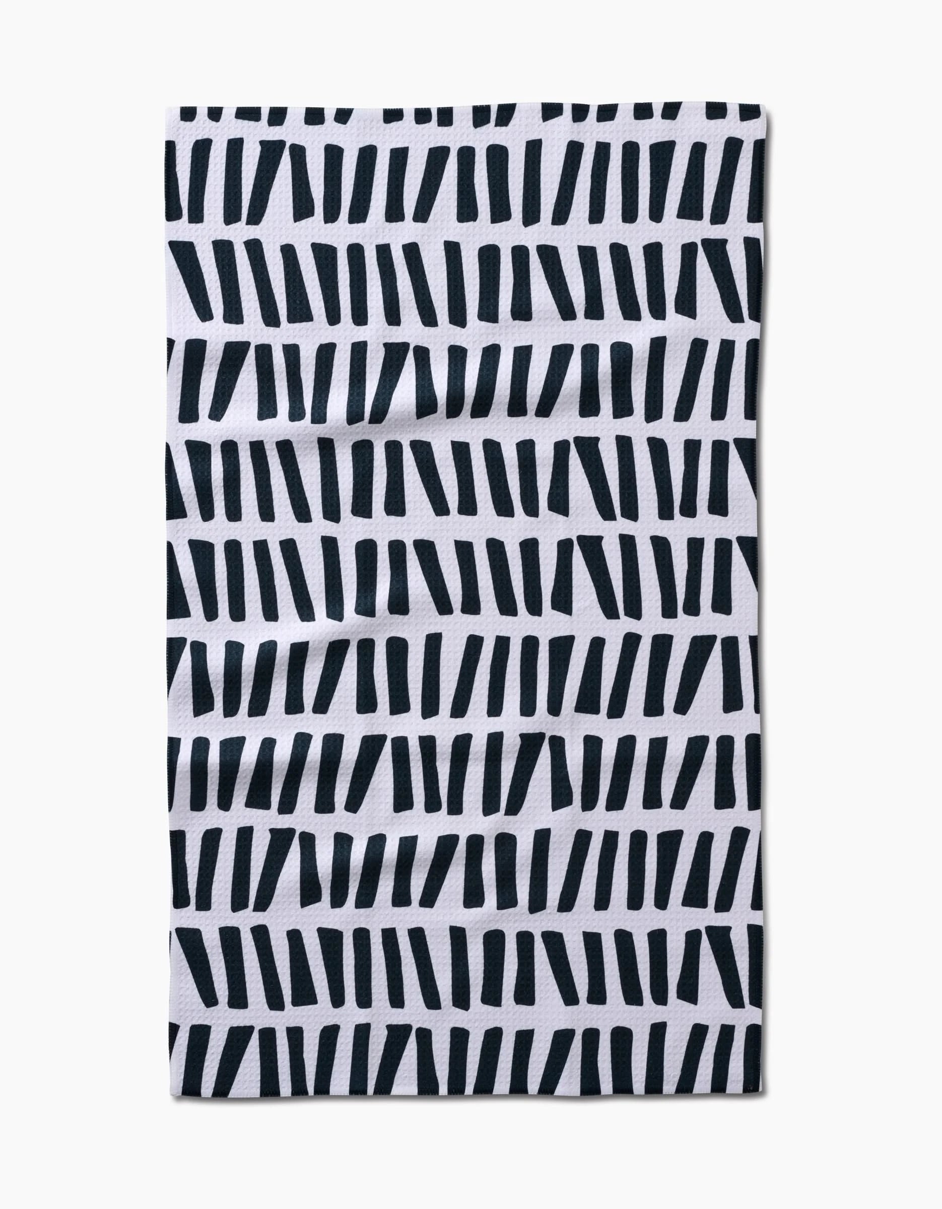 The All Lined Up tea towel by GEOMETRY is a white, ultra-absorbent rectangular towel featuring a stylish pattern of thick, staggered black lines at various angles for quick-drying functionality and modern appeal.