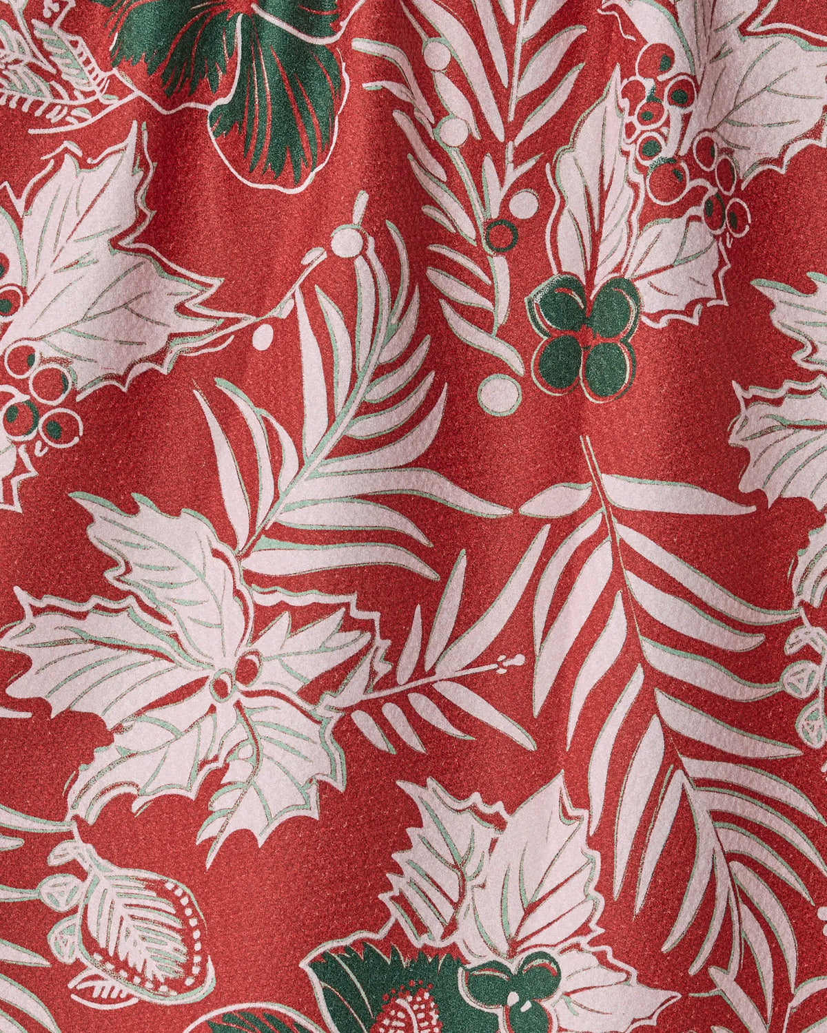 The Geometry Aloha Winters dish towel features a vibrant red fabric adorned with a festive pattern of white holly leaves, green berries, and ferns. Subtle shading and highlights enhance the holiday-themed design, while the slightly wrinkled texture adds depth and absorbency to this seasonal kitchen accessory.