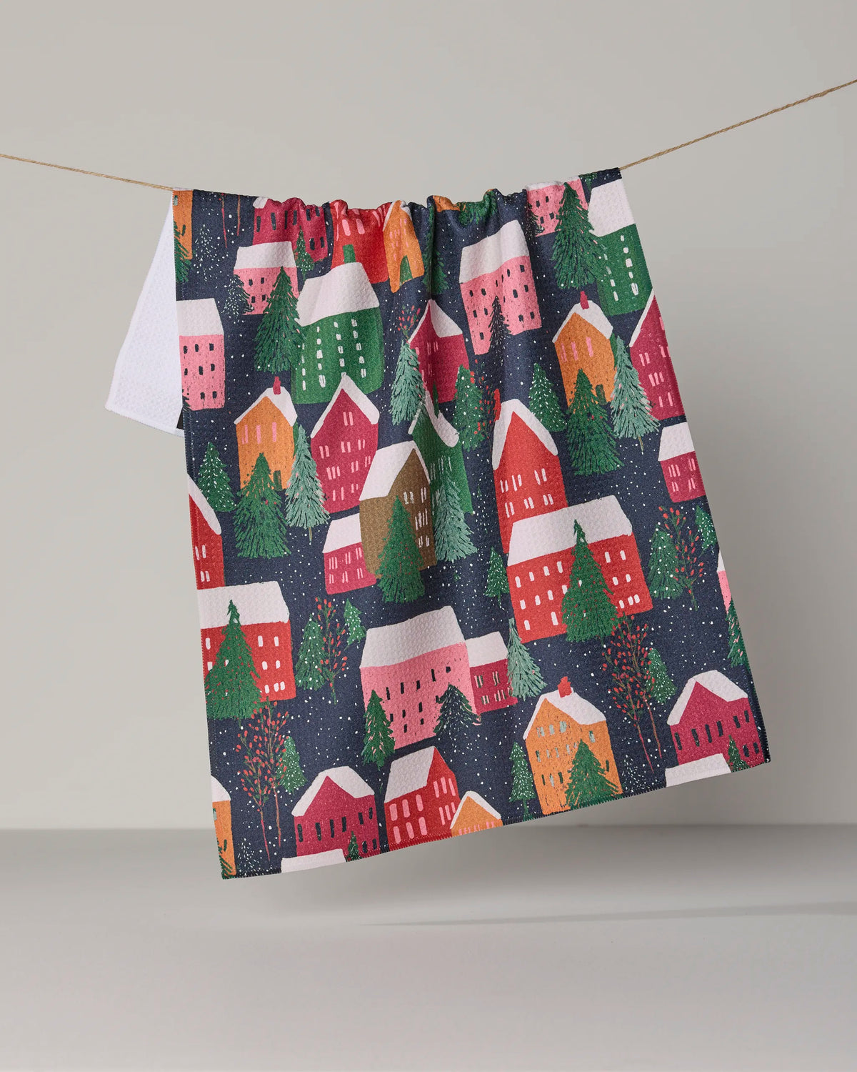 Bring both charm and sustainability to your kitchen with the “Alpine Village” tea towel by Geometry. Featuring a vibrant pattern of houses, trees, and snow hanging on a string against a neutral background, this ultra-absorbent tea towel is crafted from recycled materials for eco-friendly style.