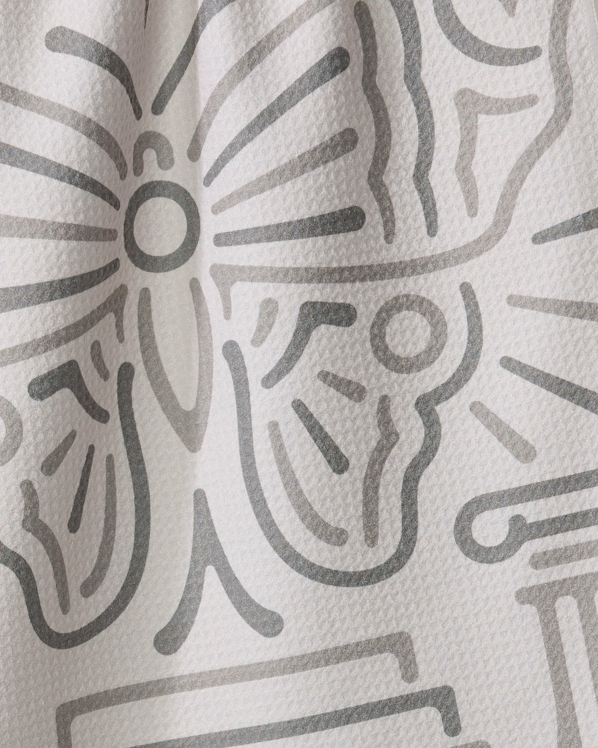 Close-up of the Alter tea towel by Adam Nienow, showcasing a textured white fabric with a simple abstract butterfly and gray shapes in line art.