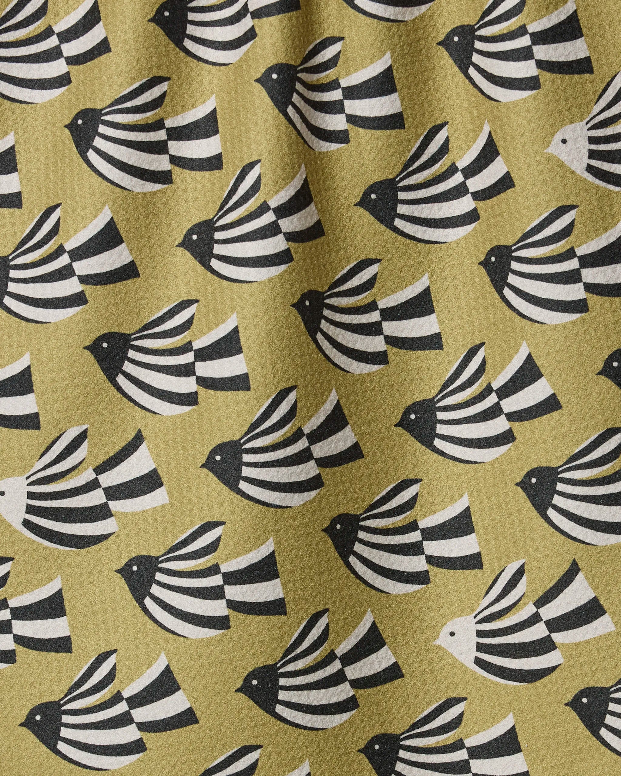 Alva by Anna Christian is a quick-drying towel with rows of stylized black and white birds with striped wings on a muted yellow background. One white bird with black stripes stands out, adding a unique touch to the design.