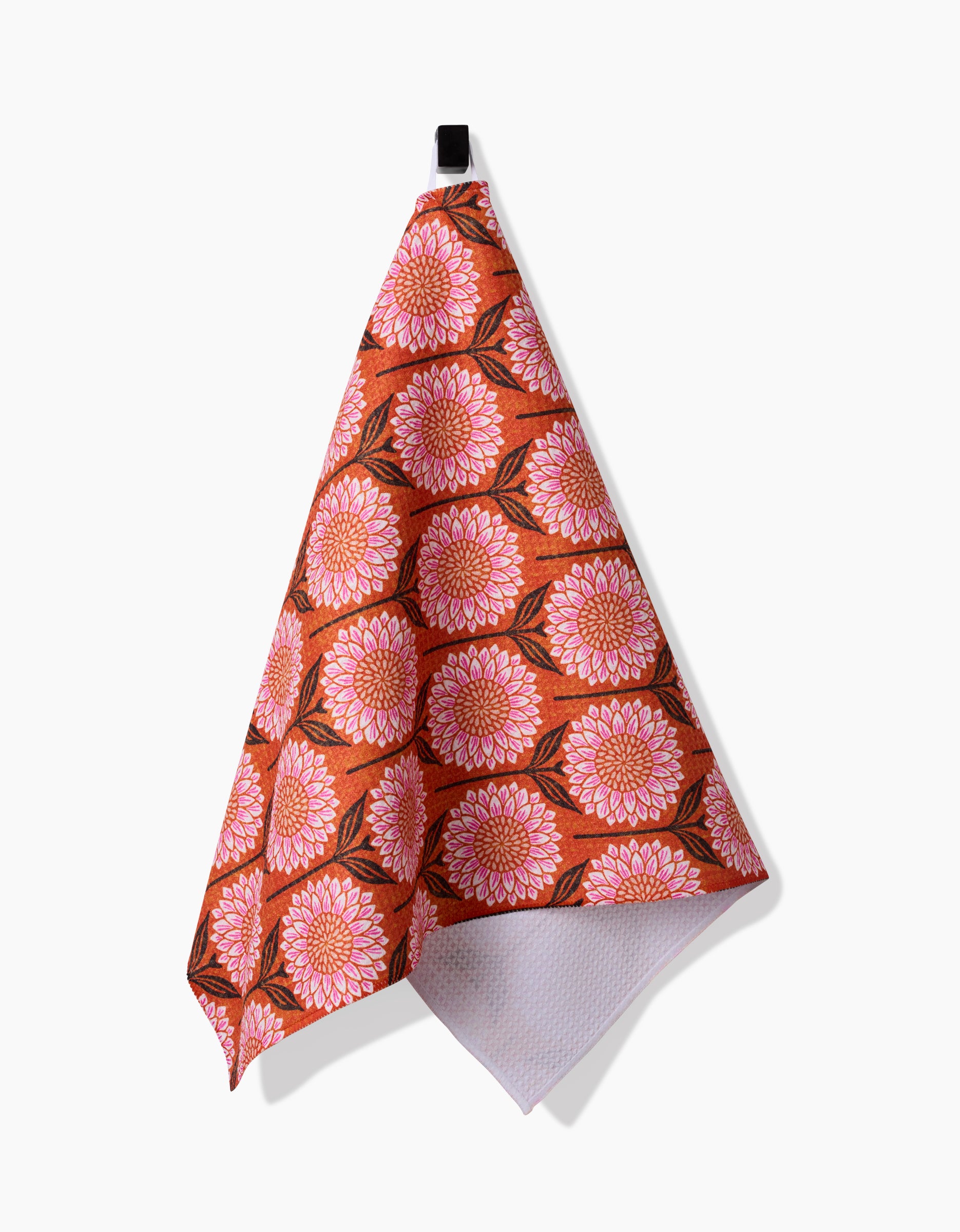 The Amy MacCready “Amber” tea towel, featuring bold pink and orange flowers with green leaves on an orange background, is made from ultra-absorbent recycled materials and shown against a white surface.