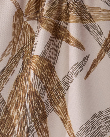 Close-up of Geometry's "Amber Wildflower" recycled kitchen towel, featuring beige fabric with an abstract pattern of brown and tan brushstrokes. The quick-drying towel is slightly folded for added depth and a textured, organic look.