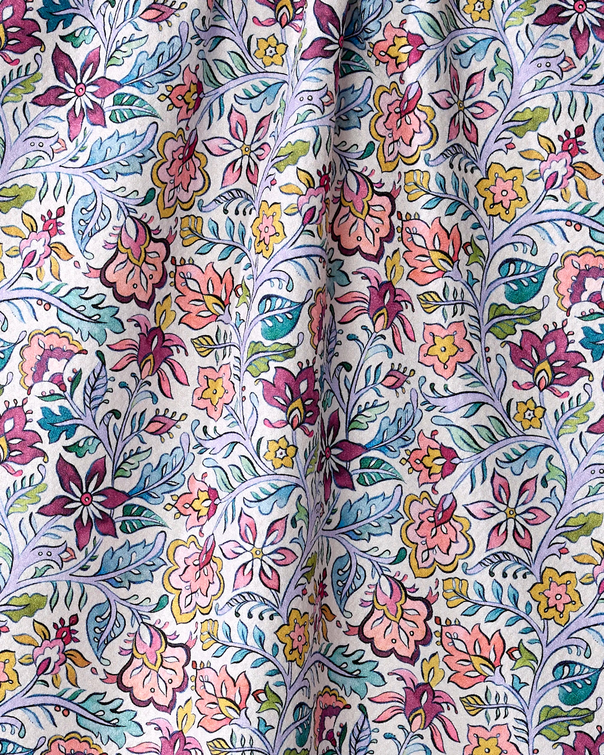 A close-up of the eco-friendly "Amethyst" kitchen towel by Maayan Alper-Swan, showcasing its colorful floral pattern with pink, yellow, and purple flowers and green-blue leaves softly draped on a light background.