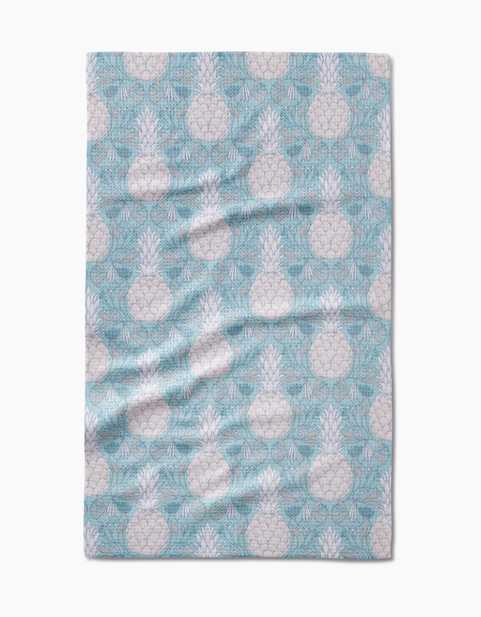 The Andre tea towel by Amy MacCready features a light blue color with a white pineapple and palm leaf pattern, crafted from Geoweave fabric. Some folds and wrinkles are visible.
