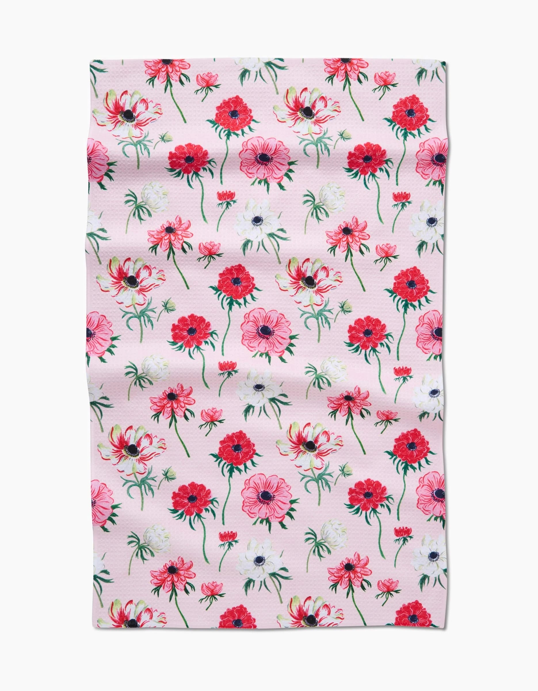 The Anemone Garden Flowers tea towel by Linda Fox features a rectangular pink design with a pattern of red, pink, and white flowers with green stems and leaves on Geoweave fabric that appears slightly wrinkled.
