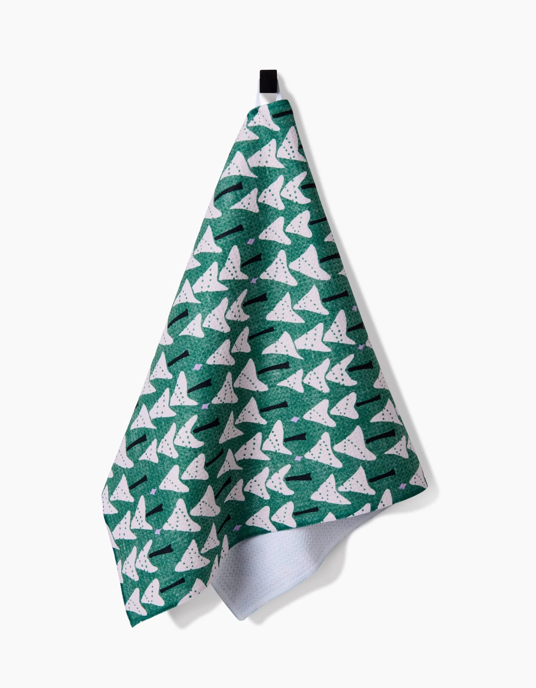 The Angelina tea towel by Amy MacCready, made from ultra-absorbent recycled materials, features a green design with white sharks and black dots. It hangs from a black loop on a plain white background—stylish and eco-friendly.