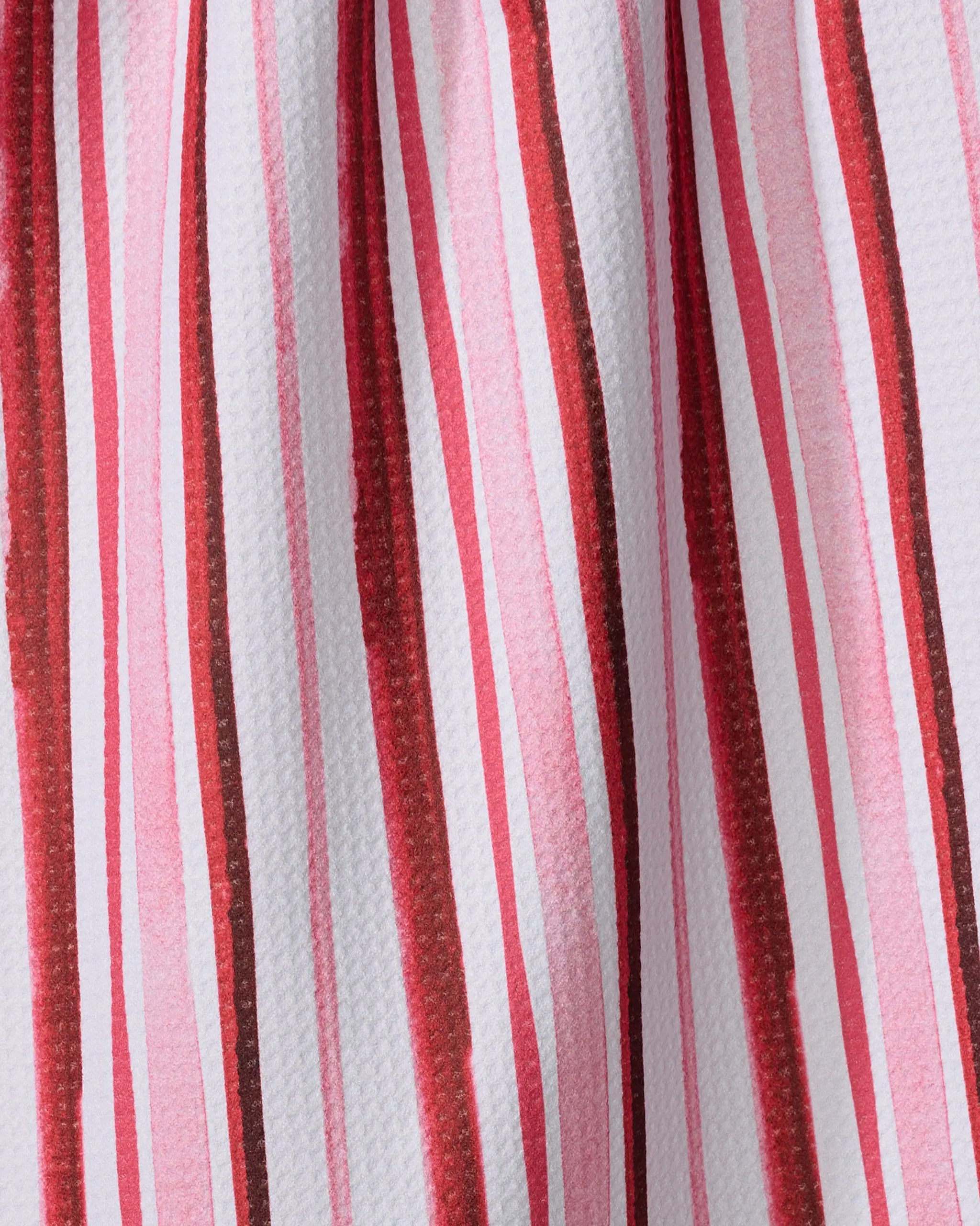 Close-up of the Aperol in Rome Stripe recycled kitchen towel by Travel Write Draw by Meagan Morrison, featuring vertical red, burgundy, and pink stripes of varying widths on white fabric for a textured, flowing look.