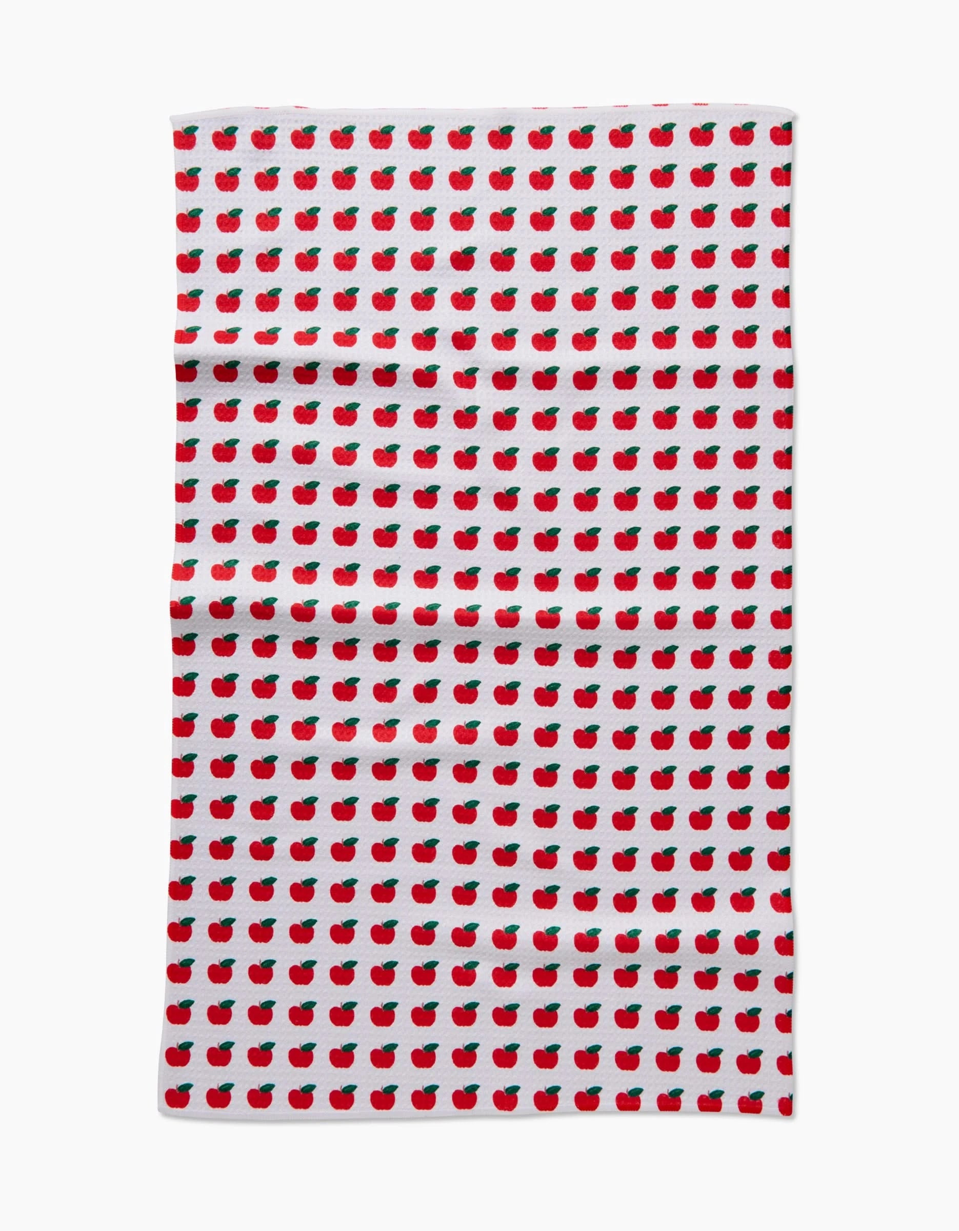 The Brittany Jepsen Apple Grove tea towel features a repeating pattern of small red apples with green leaves on a white Geoweave fabric background with a slightly wrinkled texture.