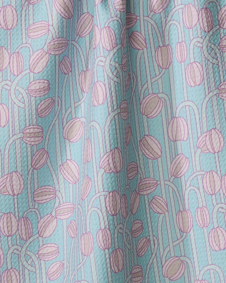 A close-up of Aqua Poppy Pods fabric by Katie O'Shea reveals light blue recycled kitchen towel material with textured pink coffee bean patterns and curving vine-like lines.
