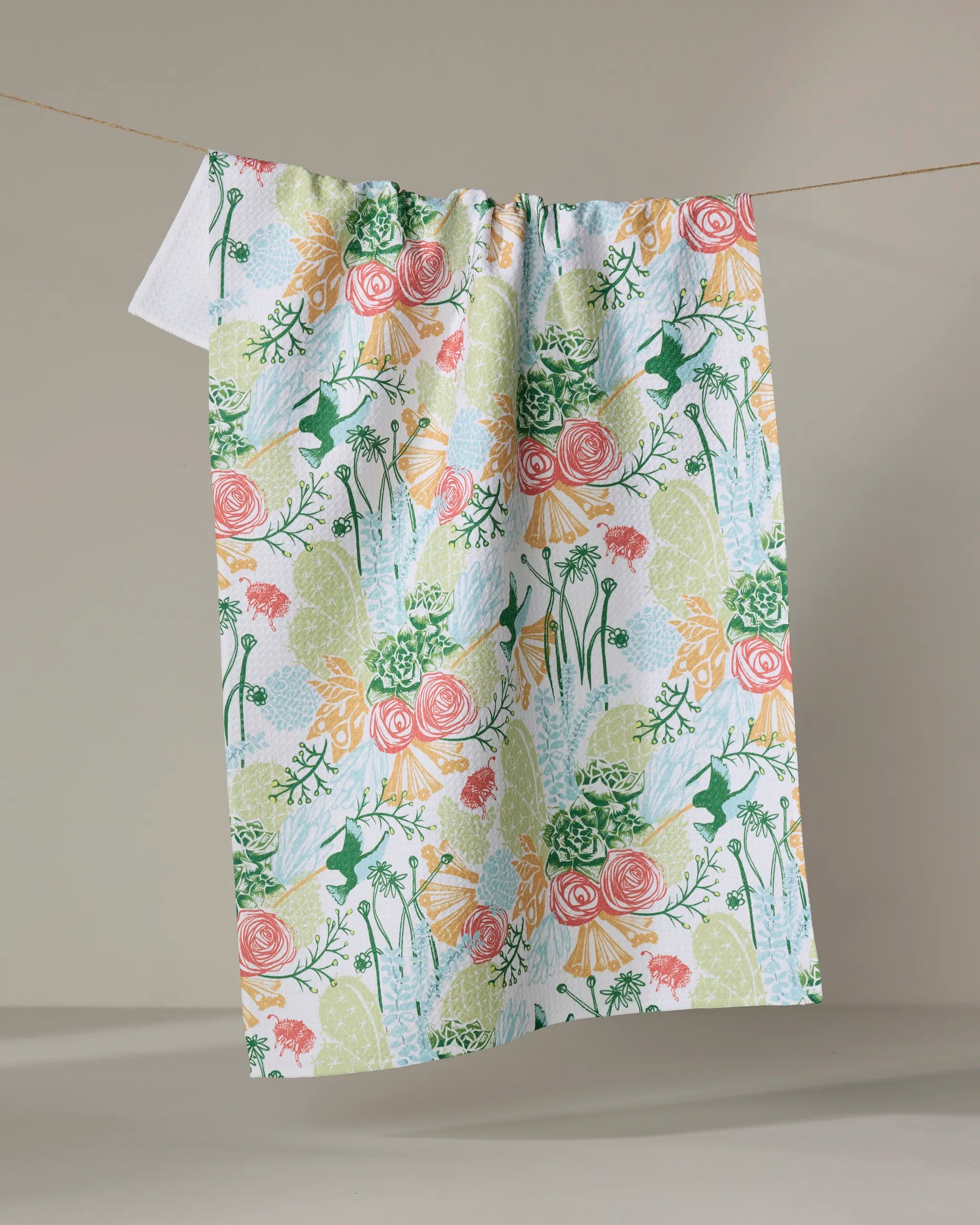 Elisabeth Wing’s “Arizona Spring” tea towel, made from recycled materials, features a vibrant green, pink, yellow, and orange floral and botanical design on white—an eco-friendly accent for your space.