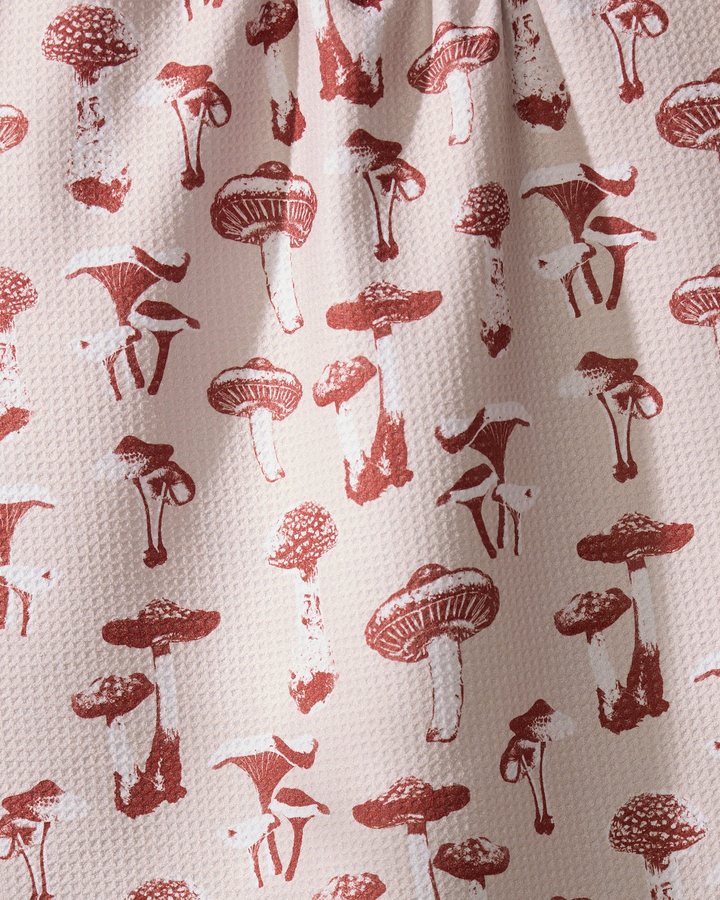 The Geometry Autumn Mushrooms tea towel features red mushroom illustrations on a textured white surface and is made from recycled materials.
