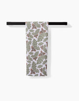 The Danelys Sidron Autumn Pines towel, featuring green oak leaves and brown acorns on white ultra-absorbent Geoweave fabric, hangs on a black horizontal towel bar against a plain white background.