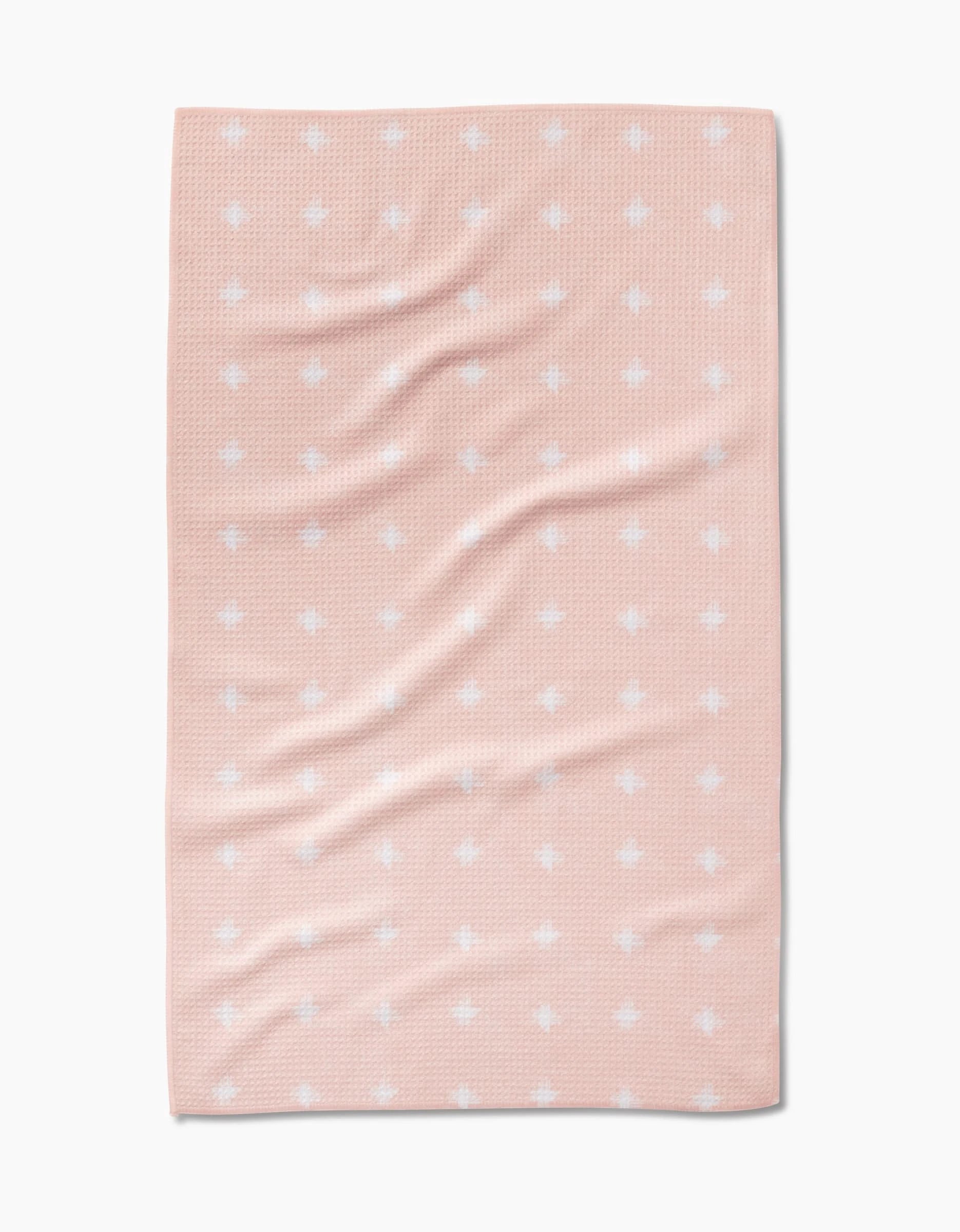 The Amy MacCready Aveline blanket is rectangular, light pink, made from Geoweave fabric with a subtle texture, and features evenly spaced small white dots. Its shown spread flat with gentle folds and wrinkles.