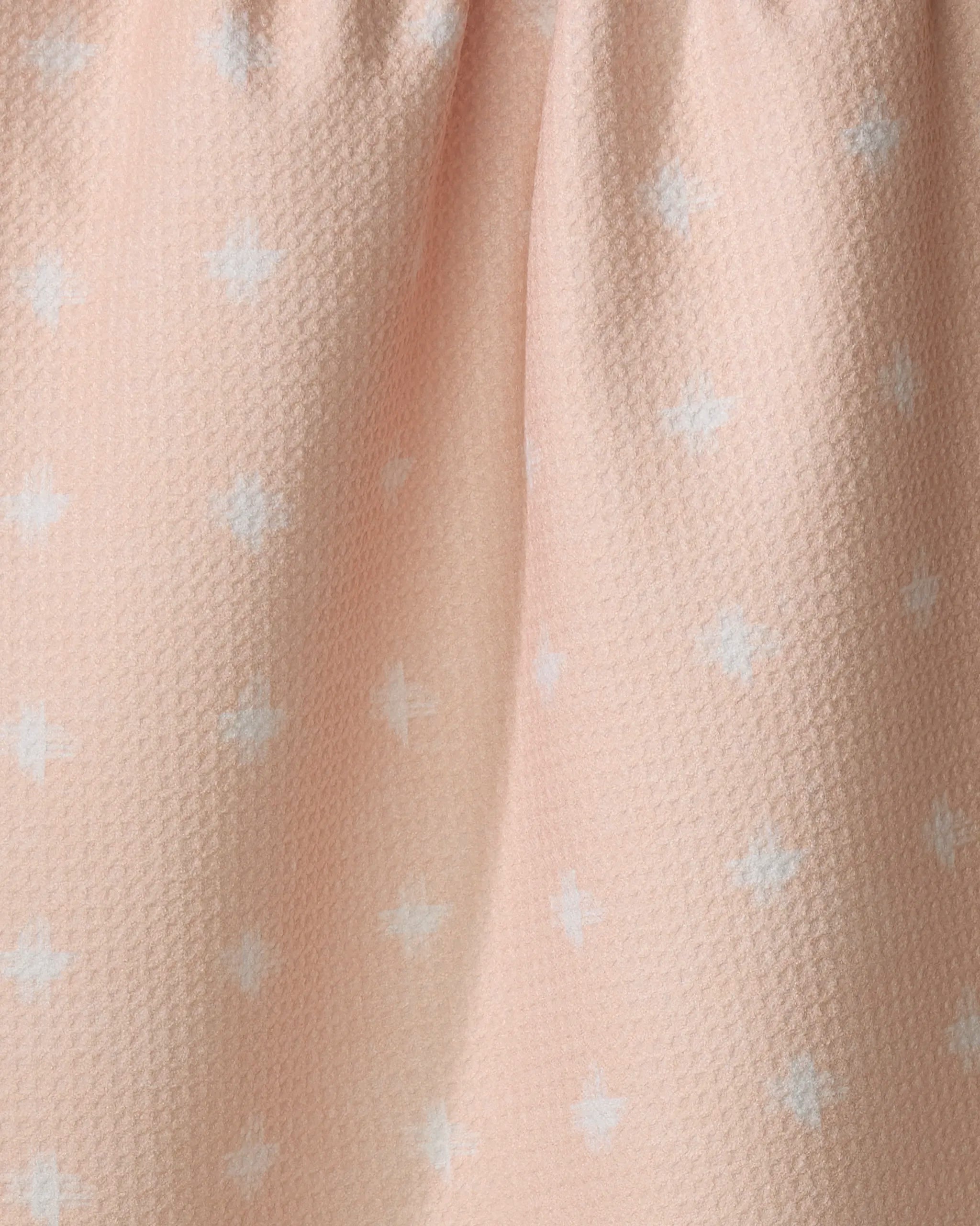The Aveline kitchen towel by Amy MacCready features a light pink, recycled fabric with a softly pleated top and a textured surface adorned with small white plus signs in a subtle repeating pattern.