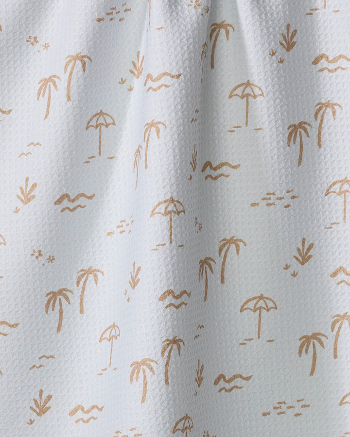 The "Beach" tea towel by Jen B. Peters features a white textured design with light brown palm trees, umbrellas, birds, waves, and grass—bringing a tropical beach vibe to your kitchen decor.