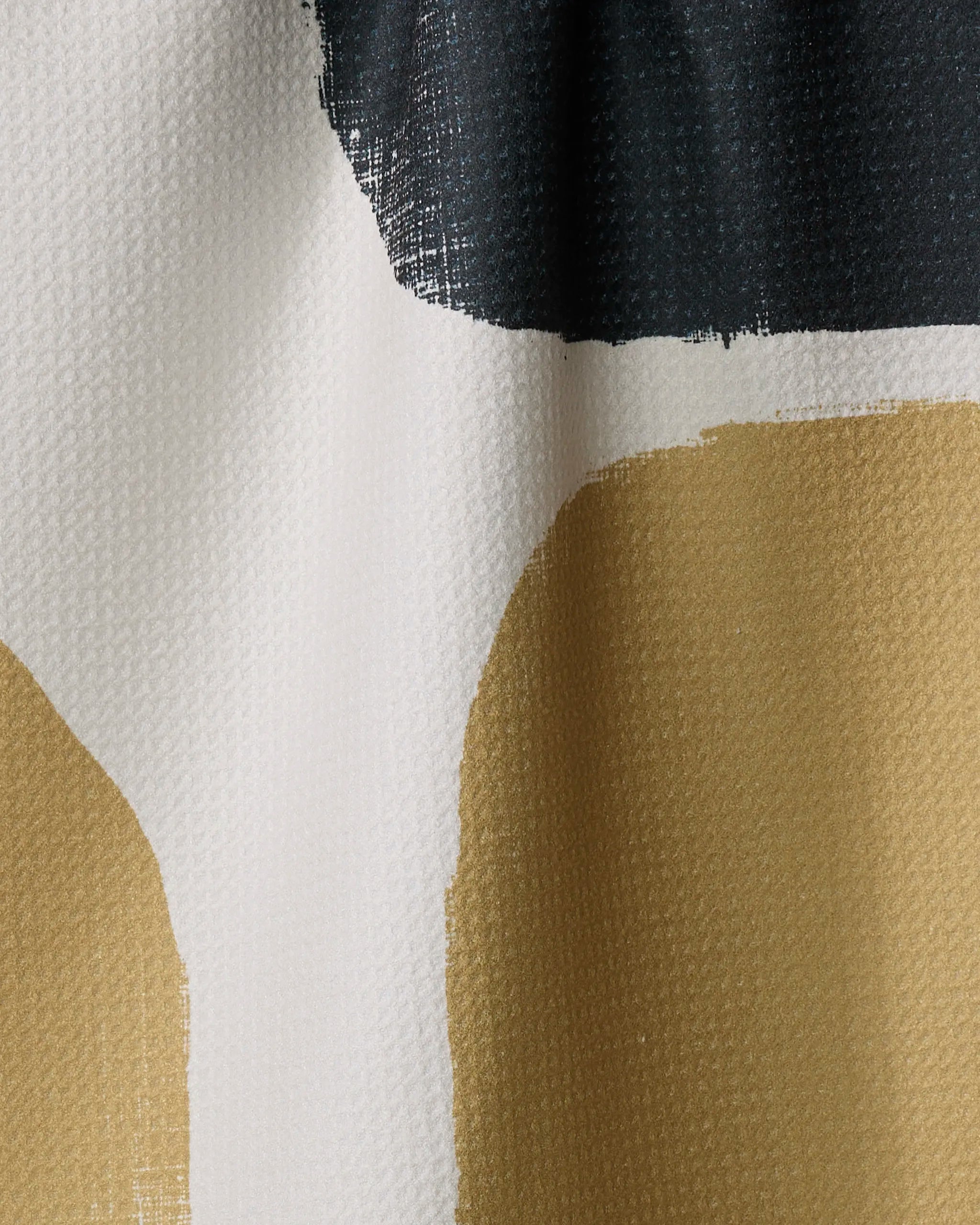 Close-up of Geometry's Bend tea towel, made from recycled materials, showcasing abstract black, white, and tan shapes with bold, uneven edges and a textured woven surface.