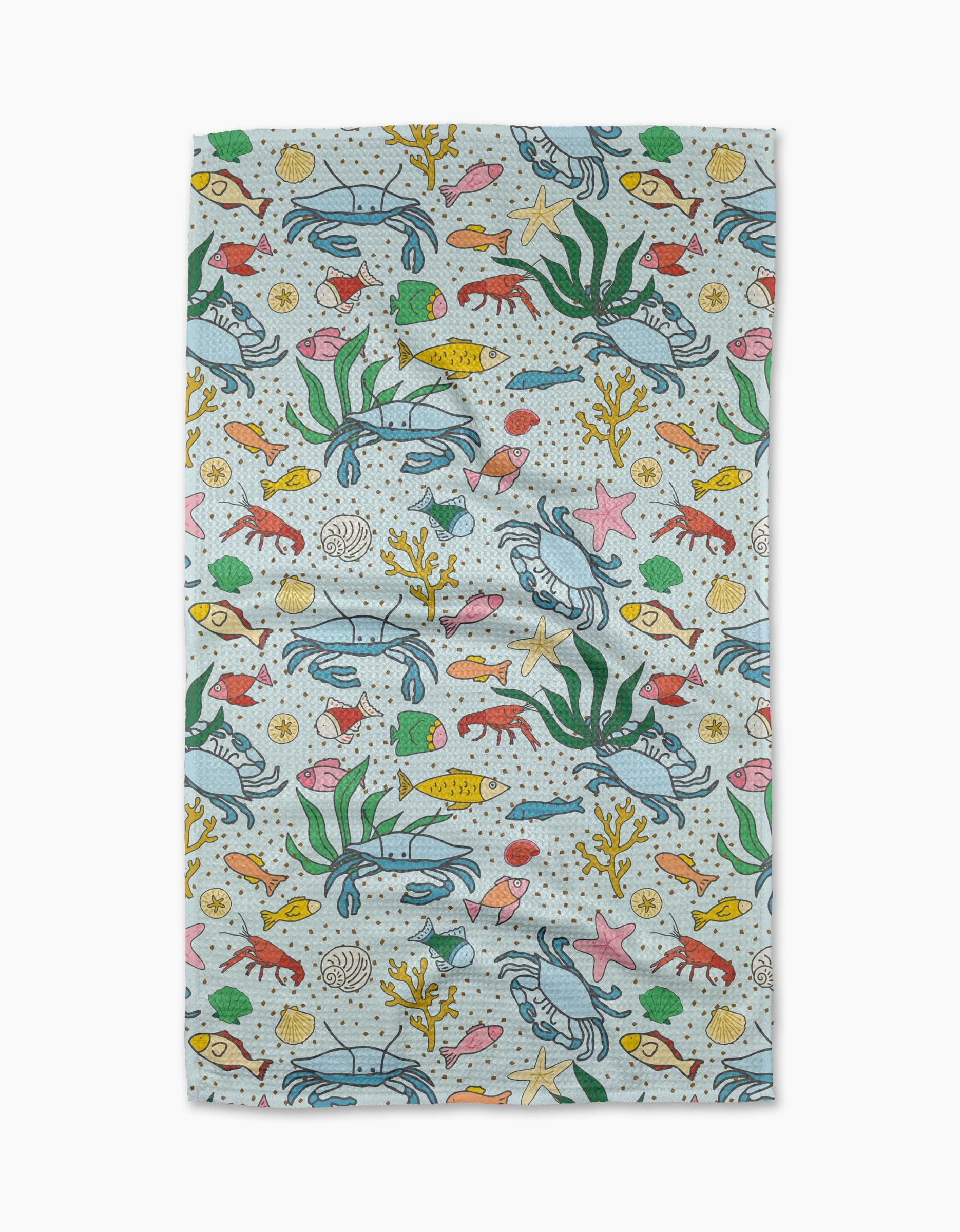 The Mindfulnice “Beneath the Waves” tea towel has a vibrant underwater scene with sea life on a light background—perfect for adding color to your kitchen décor.
